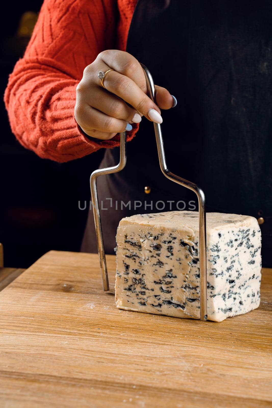 String for slicing blue cheese. Mix of cheeses on plate. Slicing dorblu, gorgonzola, roquefort. French gourmet cuisine