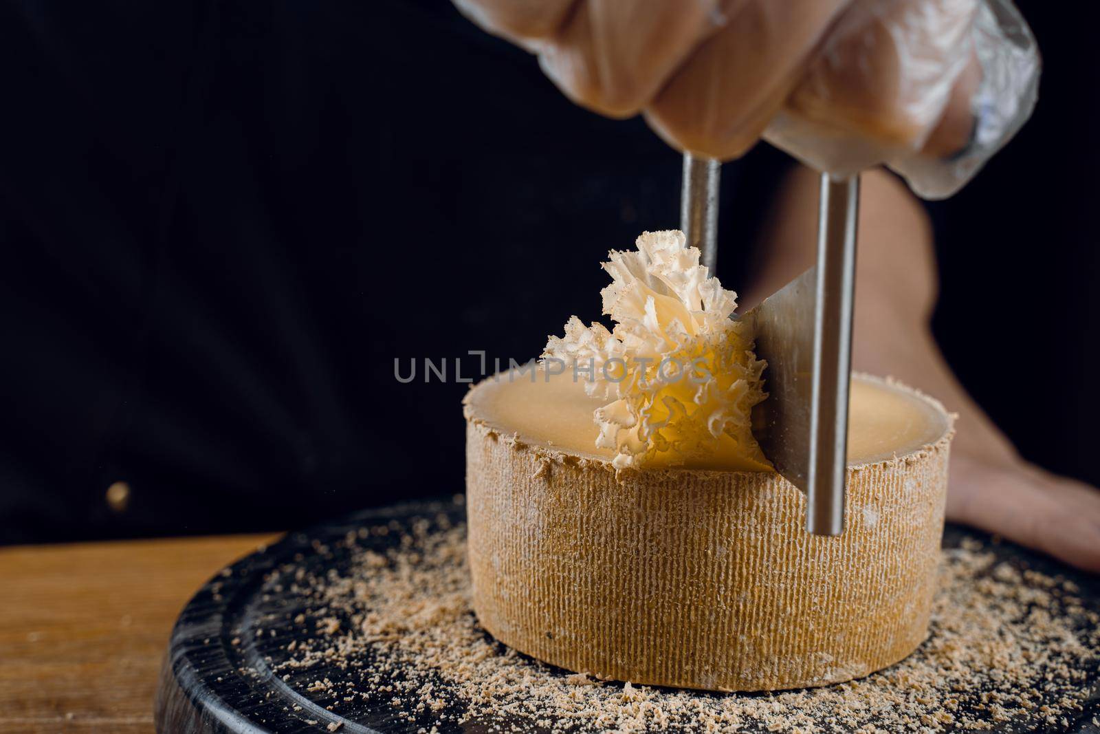 Shaving tete de moine cheese using girolle knife. Monks head. Variety of Swiss semi-hard cheese made from cows milk.