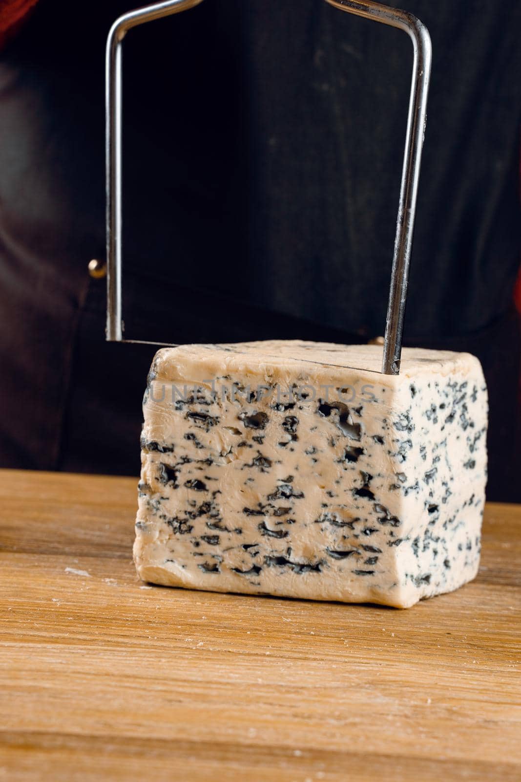 String for slicing blue cheese. Mix of cheeses on plate. Slicing dorblu, gorgonzola, roquefort. French gourmet cuisine. by Rabizo