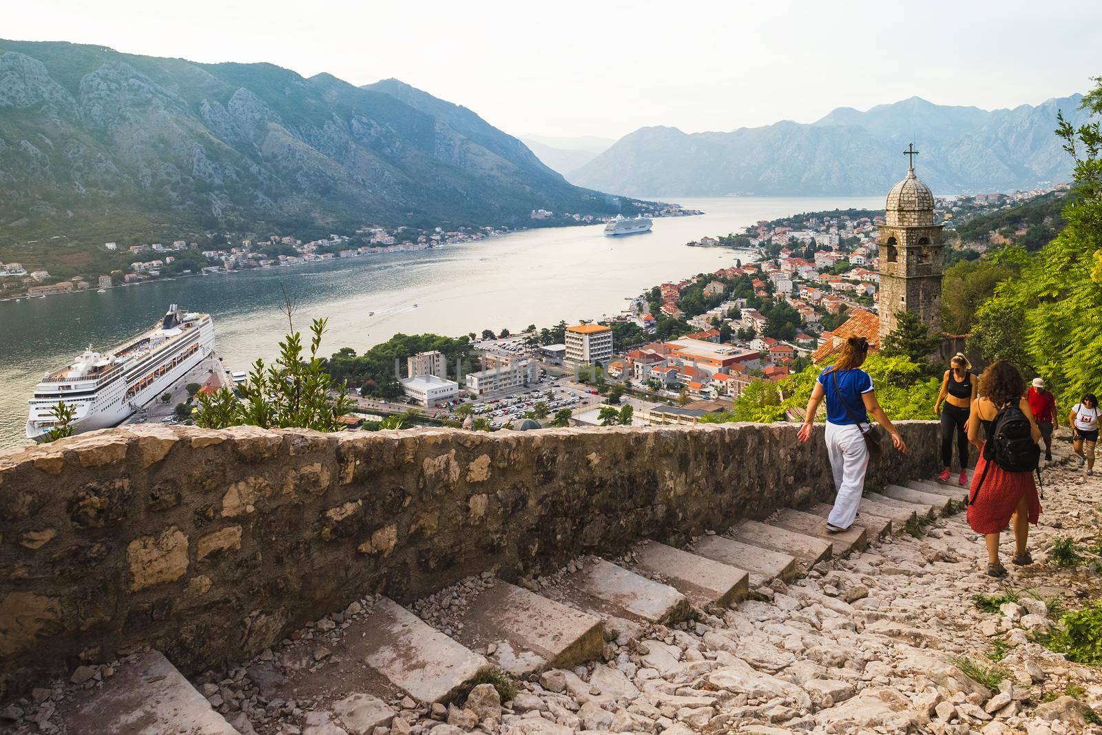 KOTOR, MONTENEGRO - September 16, 2019: Tourists climbing up and down the stairs of the ancient fortress ruins in the Bay of Kotor and old city of Kotor in Montenegro