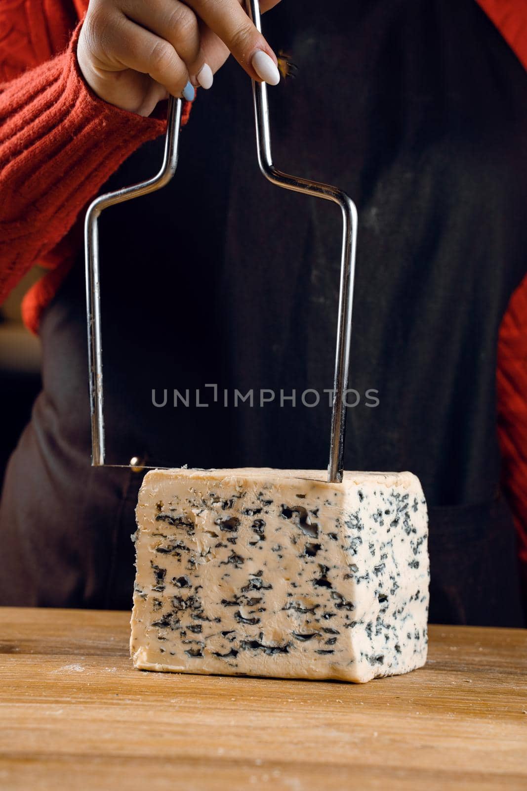 String for slicing blue cheese. Mix of cheeses on plate. Slicing dorblu, gorgonzola, roquefort. French gourmet cuisine