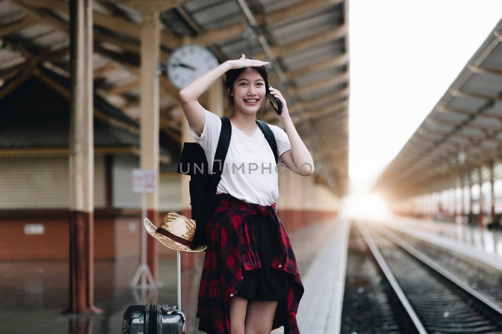 Young traveler woman looking for friend planning trip at train station. Summer and travel lifestyle concept.