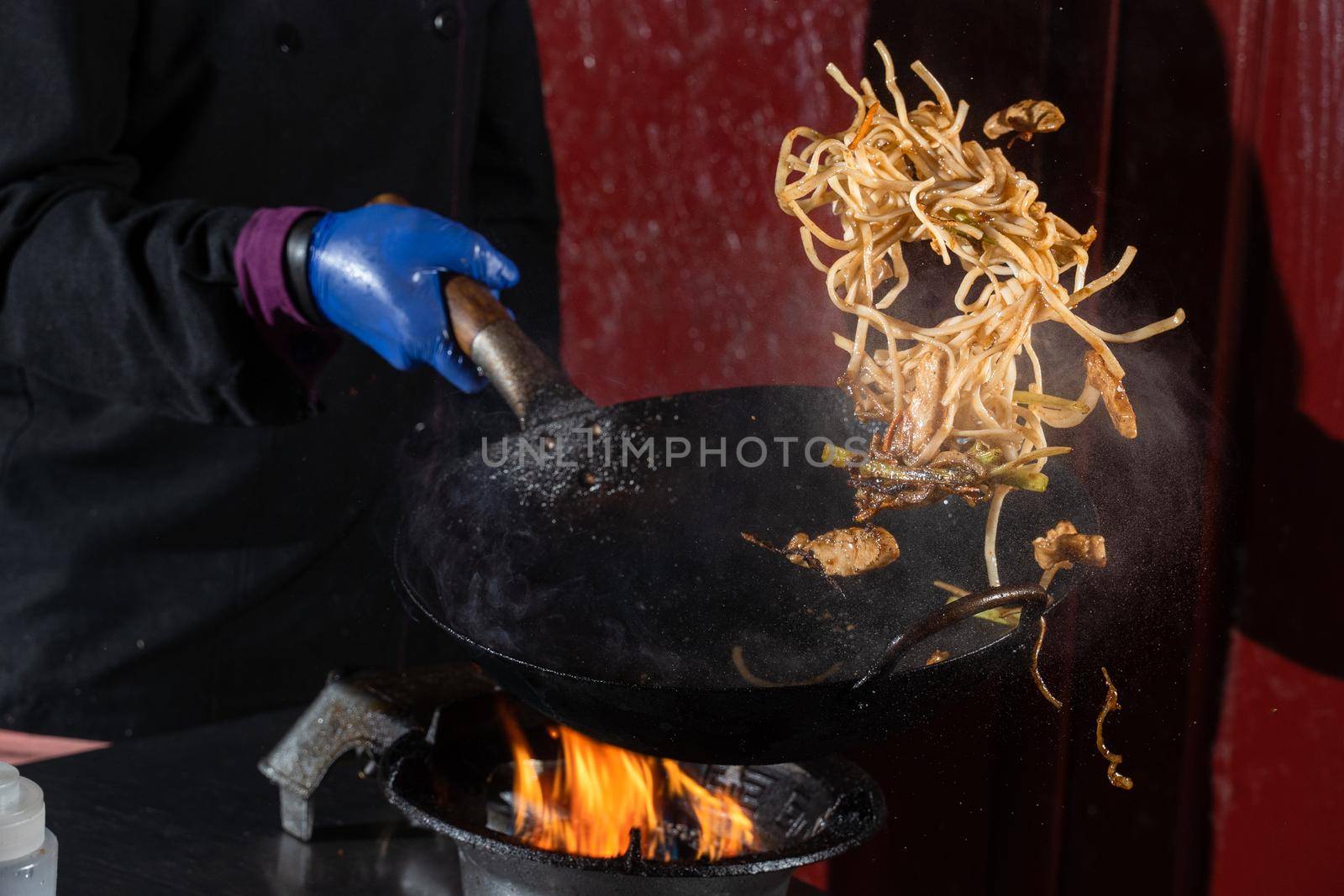 Flying noodles for wok box with meat, soy sauce fried in a wok pan, street food.