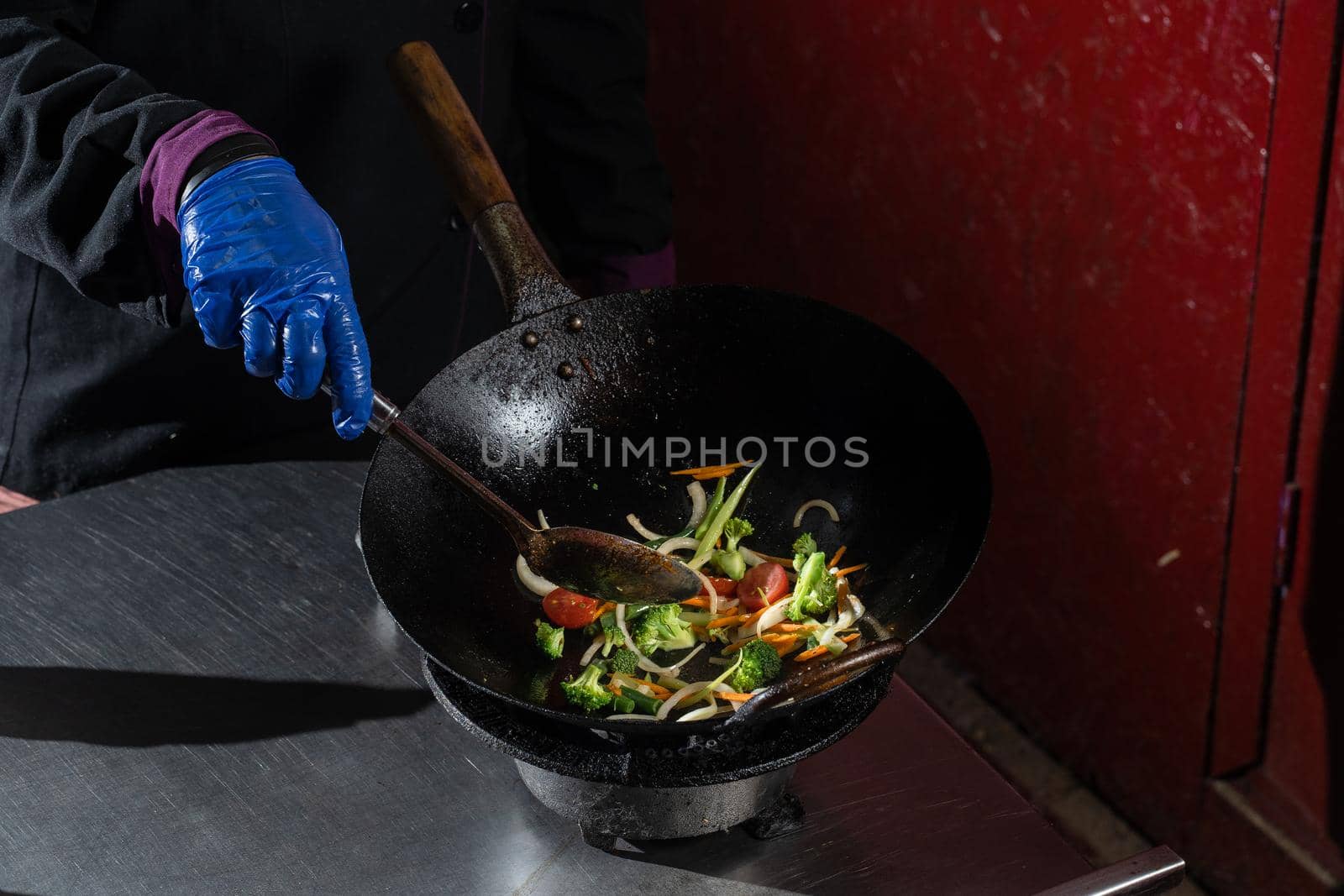 Frying vegetables in a wok pan onions, broccoli, tomatoes cherry, carrot, asparagus.