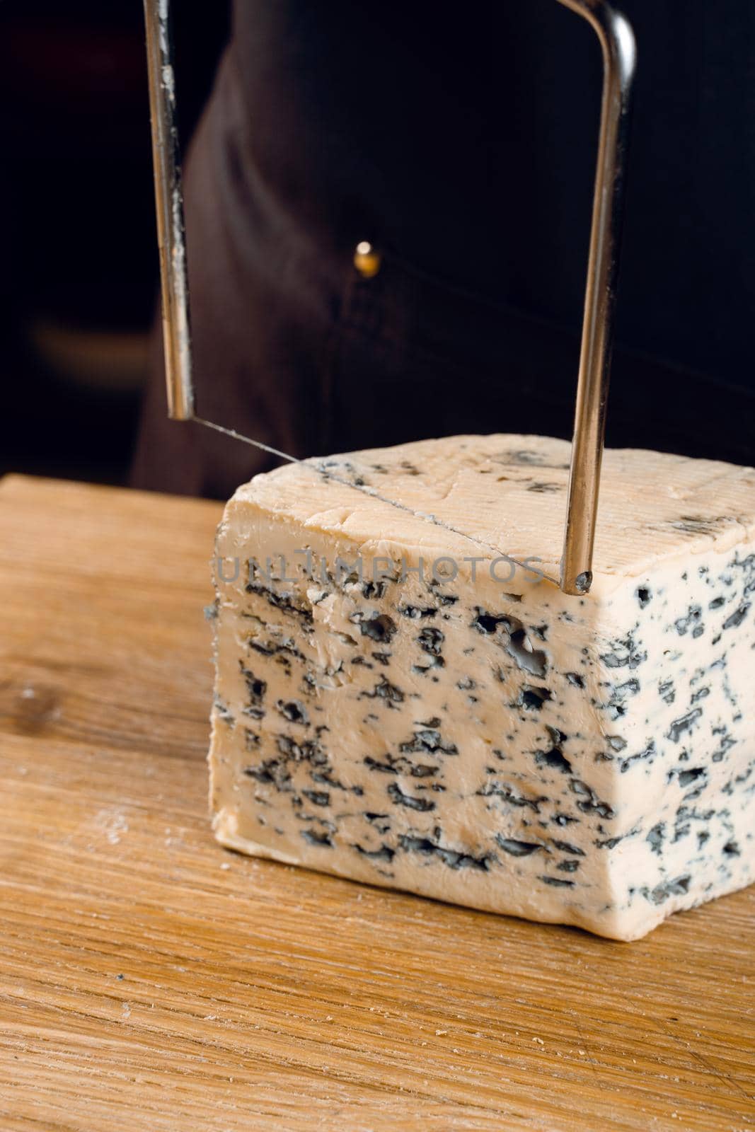 String for slicing blue cheese. Mix of cheeses on plate. Slicing dorblu, gorgonzola, roquefort. French gourmet cuisine. by Rabizo