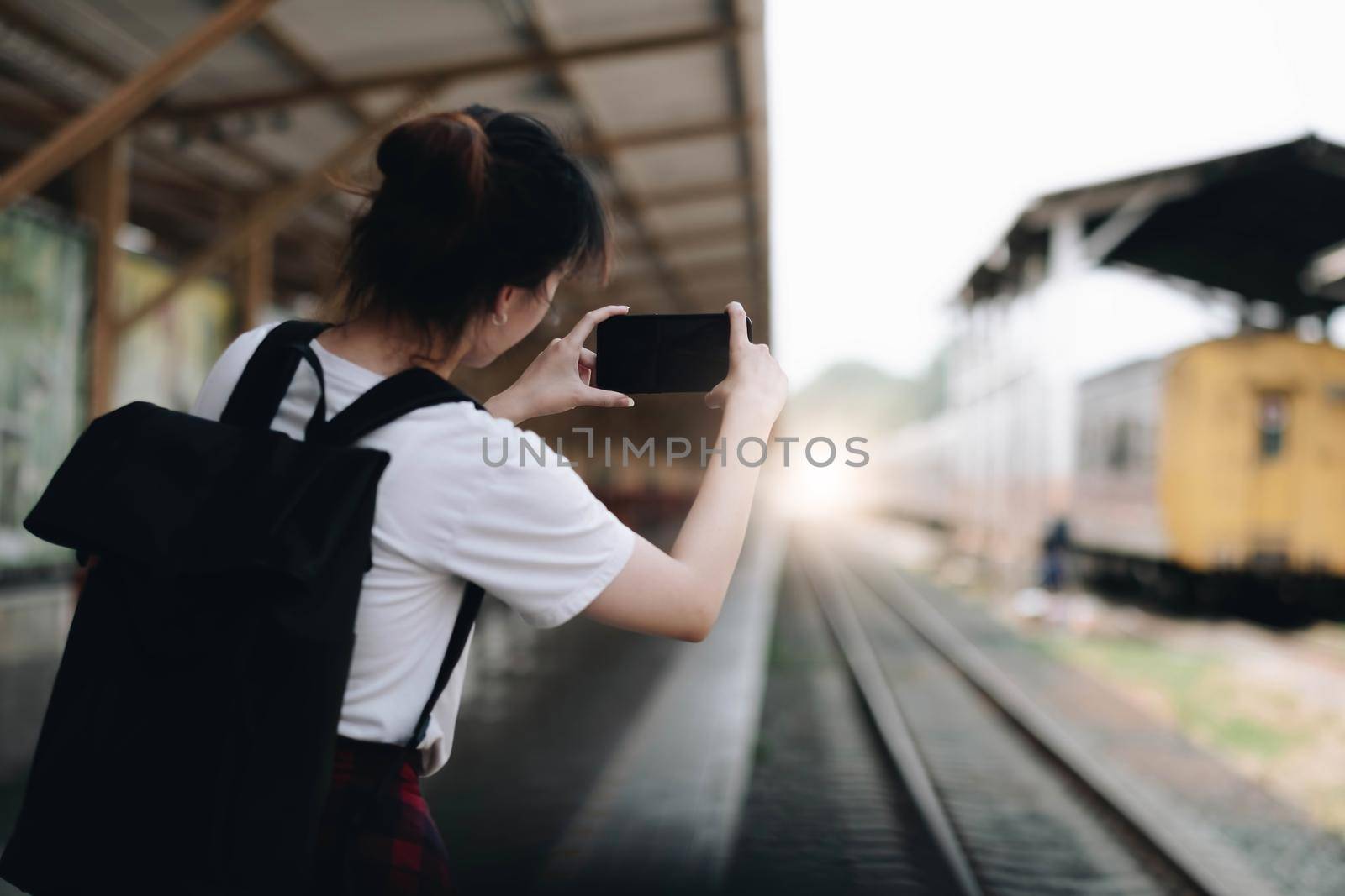Tourist woman aling selfie with a smartphone while at the train station. Enjoying travel concept. Girl using smartphone while at the railway station platform..