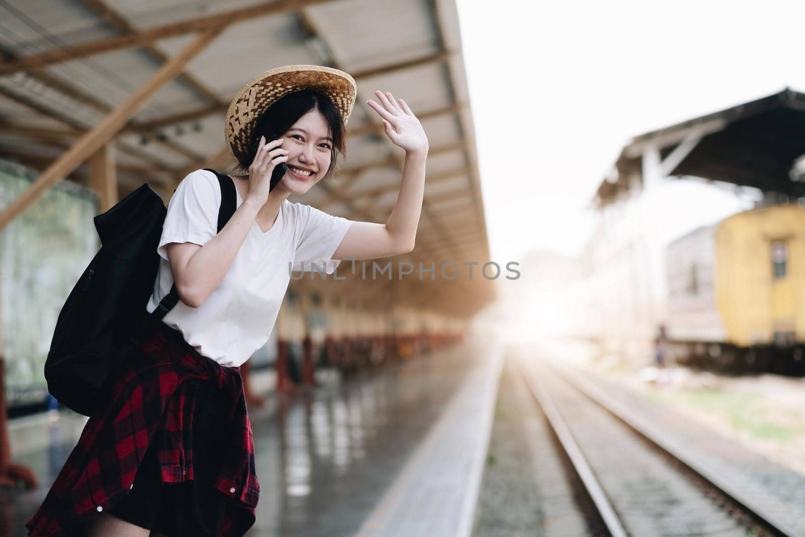 Young traveler woman looking for friend planning trip at train station. Summer and travel lifestyle concept by wichayada