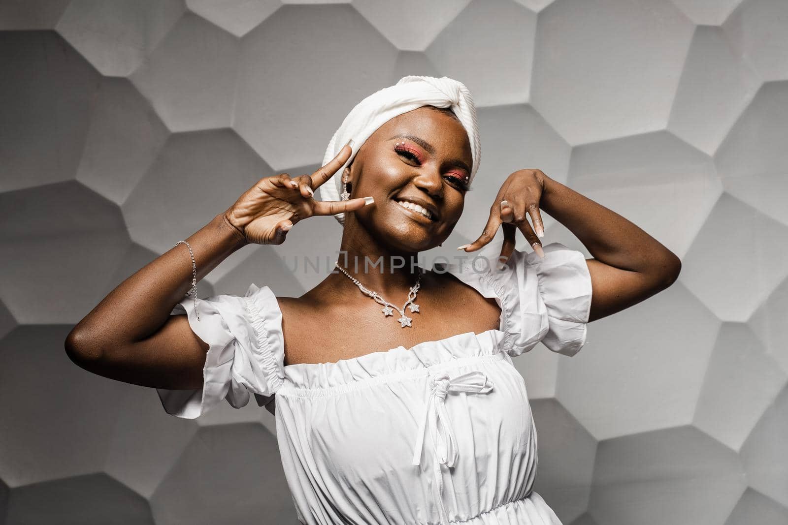 Black muslim woman holding up 2 fingers have party. African girl is celebrating her birthday and having fun.