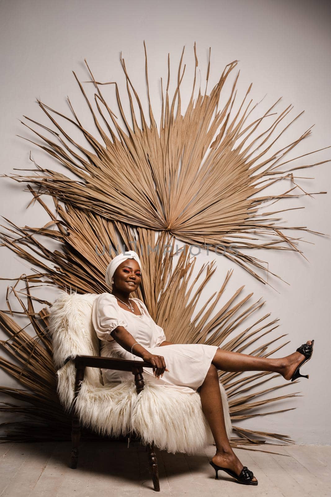 Black muslim business woman is sitting on the sofa. Confident lady weared white dress and headscarf