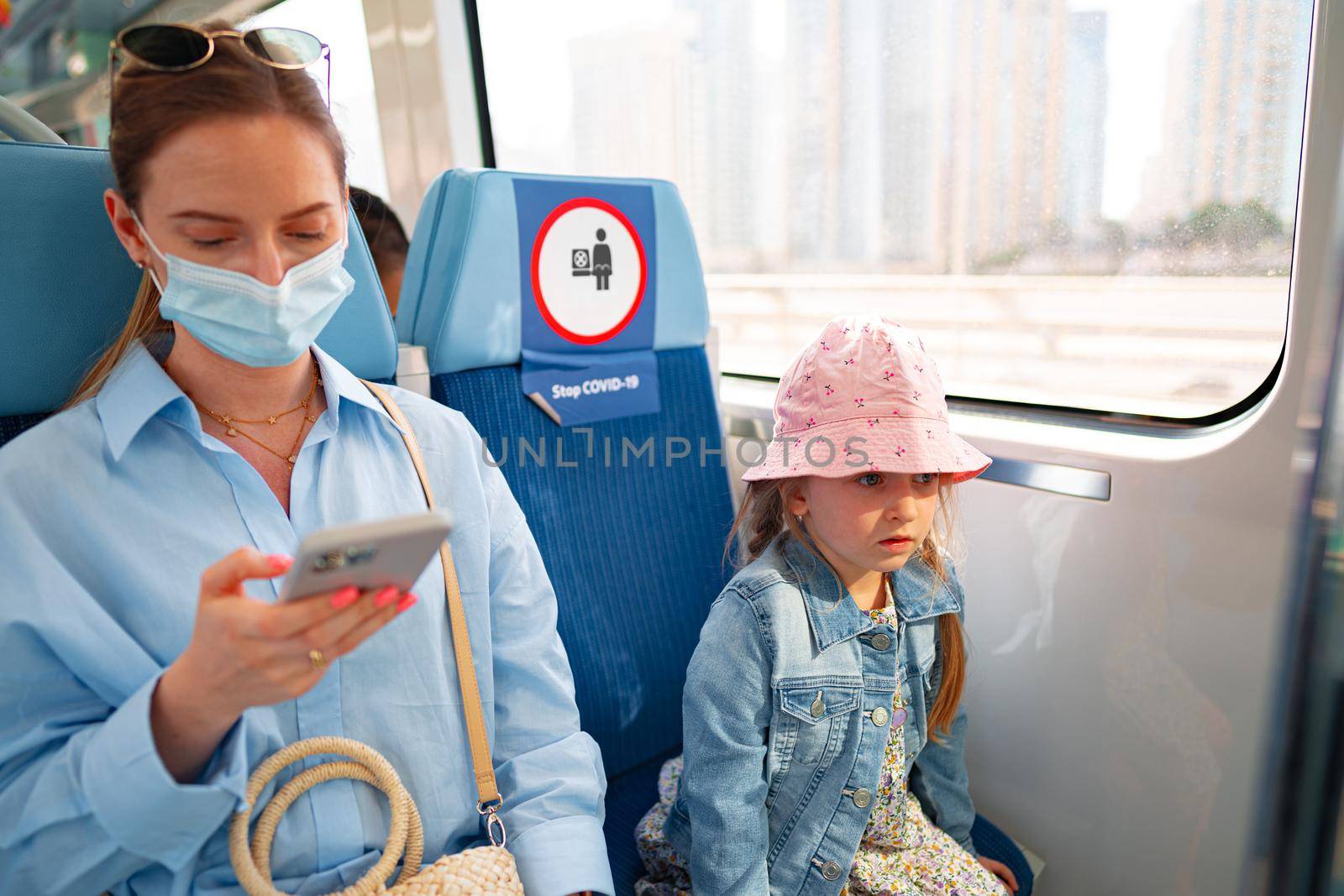 Dubai, United Arab Emirates - MARCH, 2020: Woman in face mask and her little daughter sitting in carriage of Dubai metro