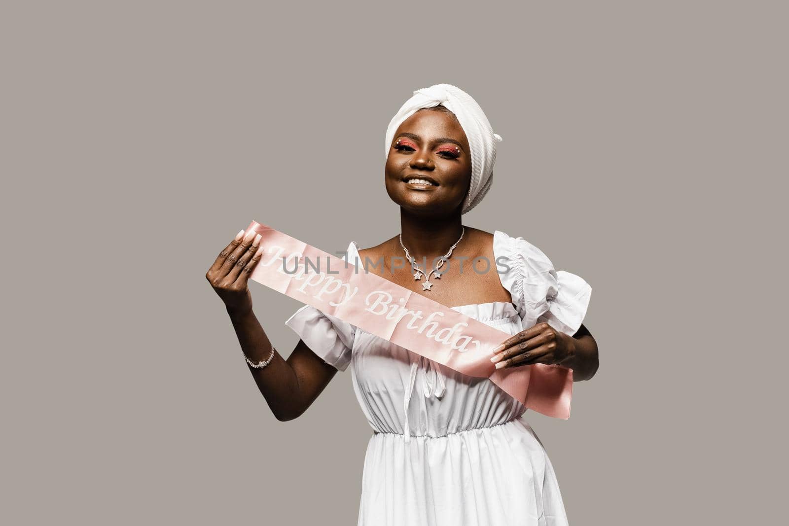 Happy muslim woman with birthday ribbon on gray background. Black african woman is celebrating her birthday