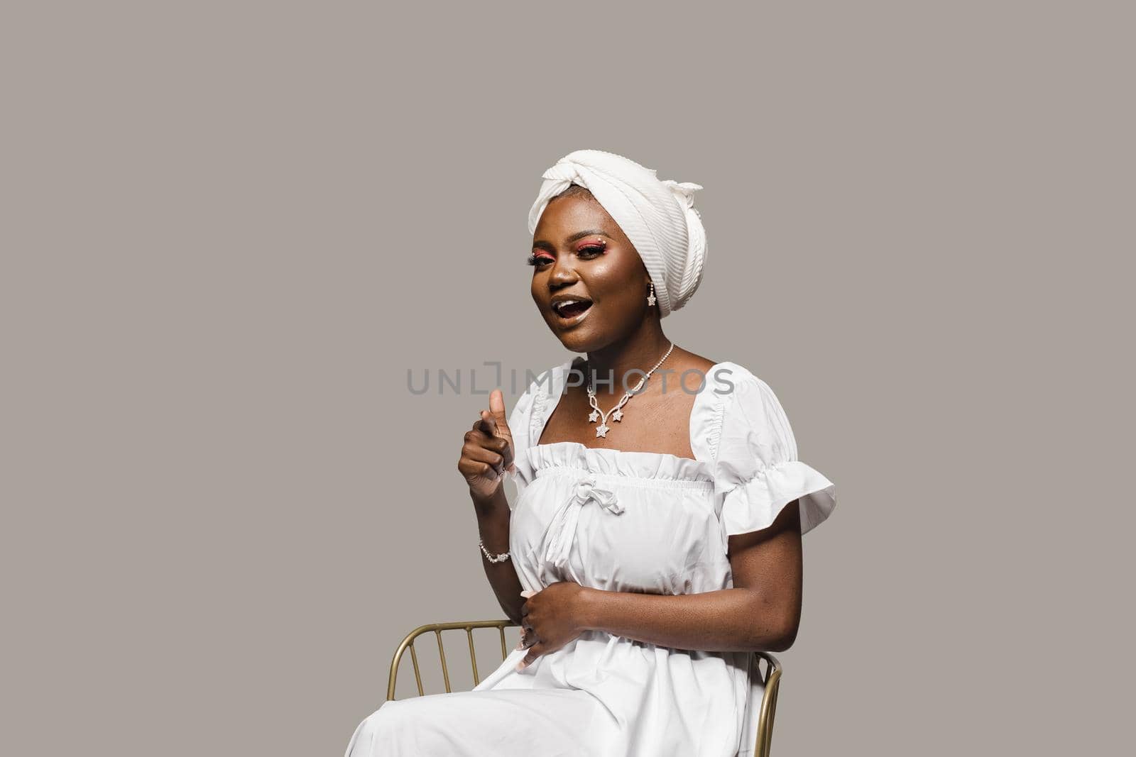 Black muslim woman is pointing to you on gray background. African model is smiling. by Rabizo