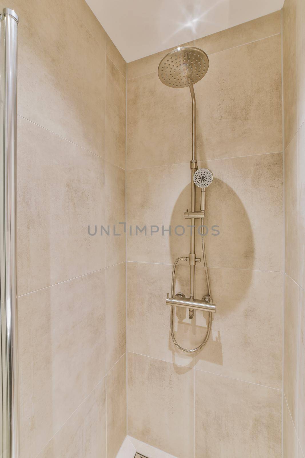 Shower tap and levers installed on beige marble wall in modern bathroom at home
