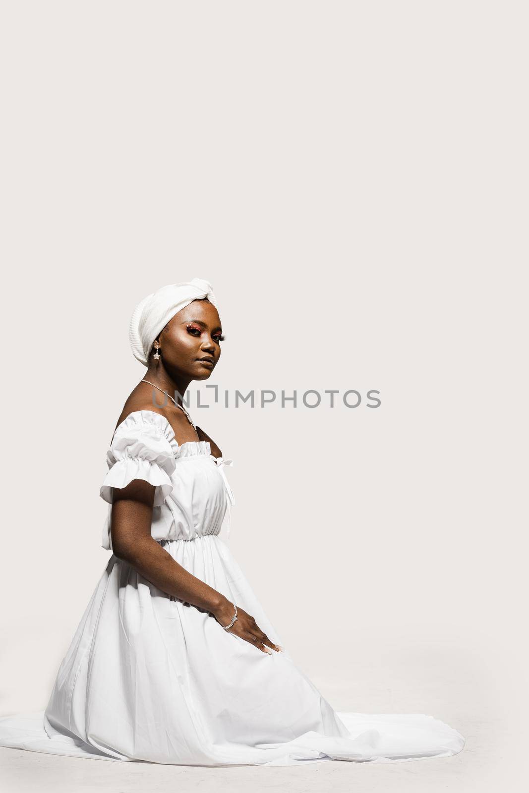 Black muslim woman is praying solat. Attractive woman in white dress sit and pray on whita background