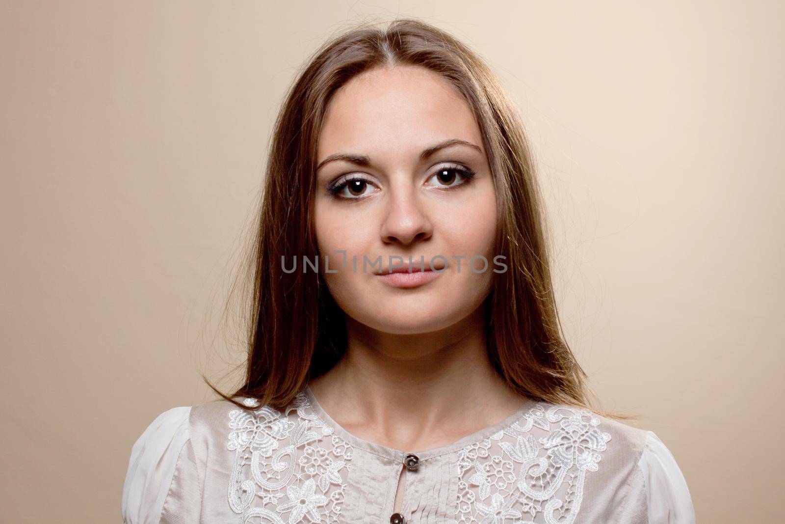 Portrait of fashionable young woman weared in light grey evening dress on biege background