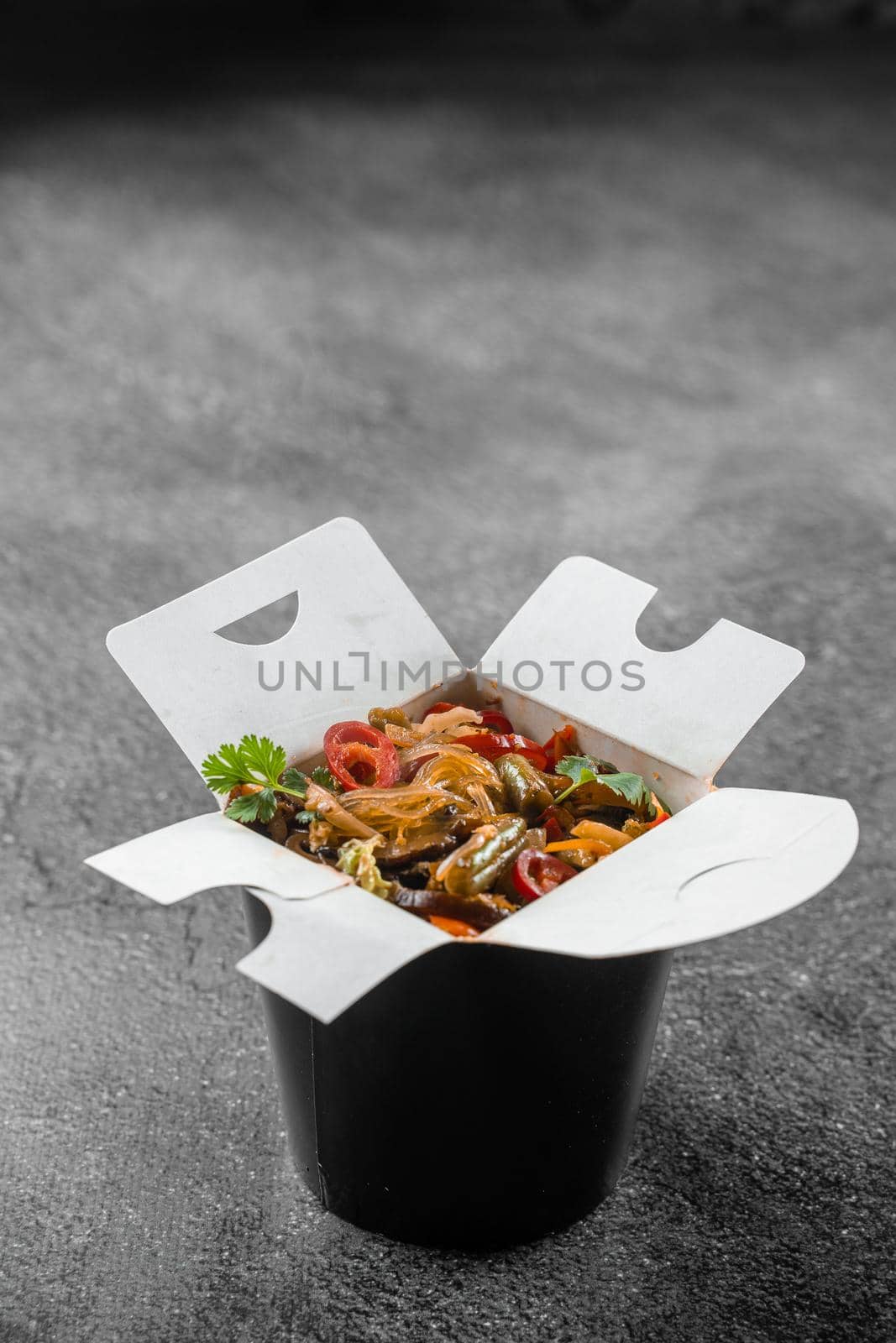 Wok in box rice noodles in black food container. Fast food delivery service. Takeaway chinese street meal