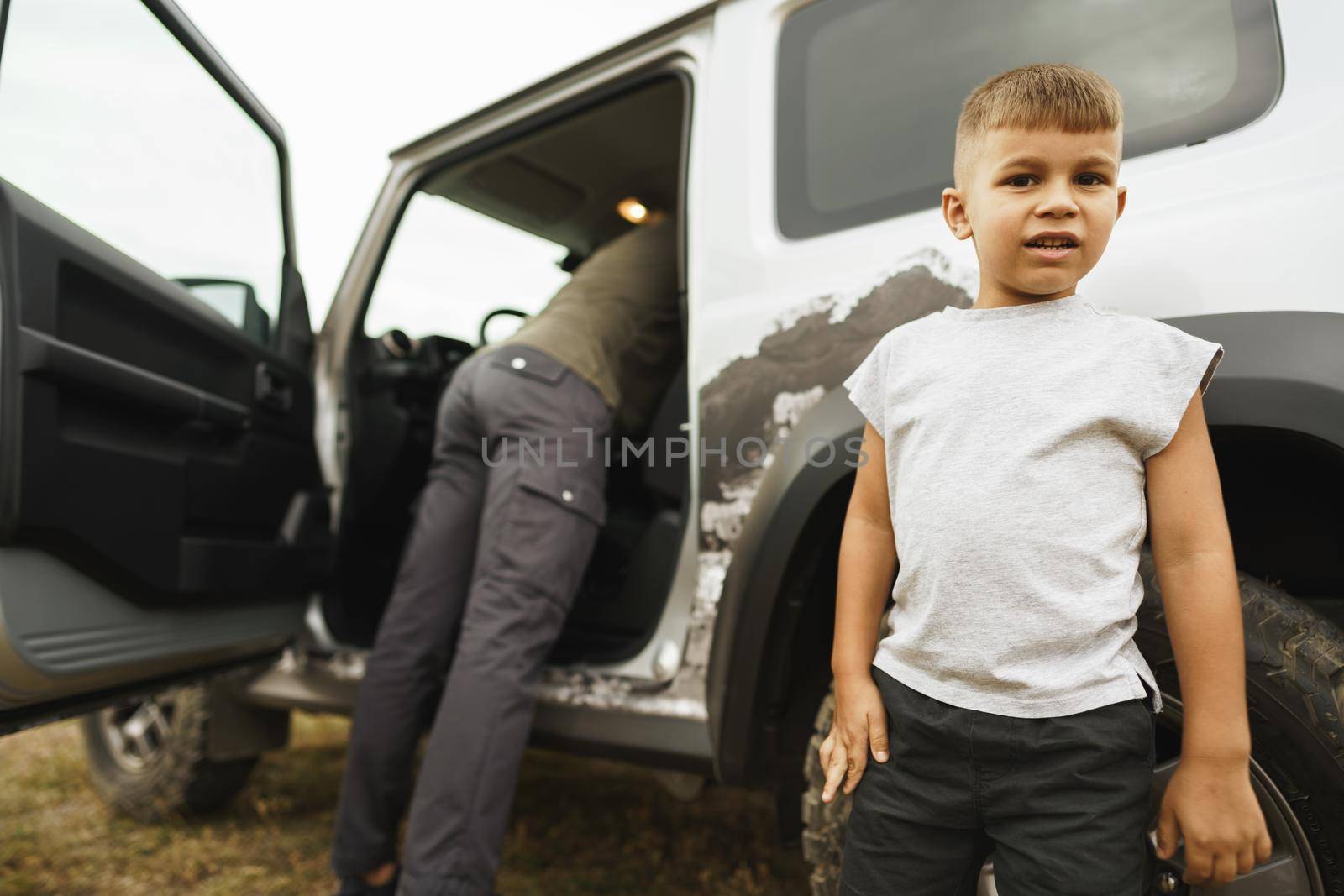 Father and little son standing near car on road trip, close up