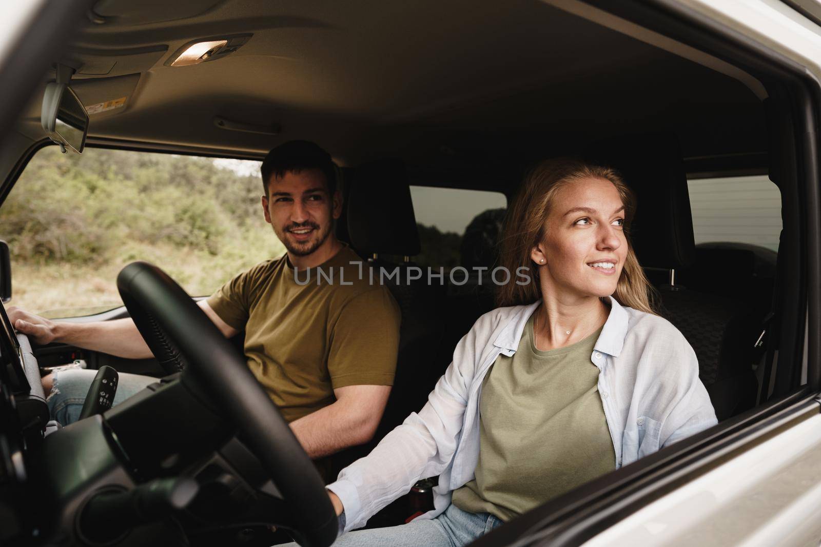 Beautiful young smiling couple sitting on front passenger seats and driving a car