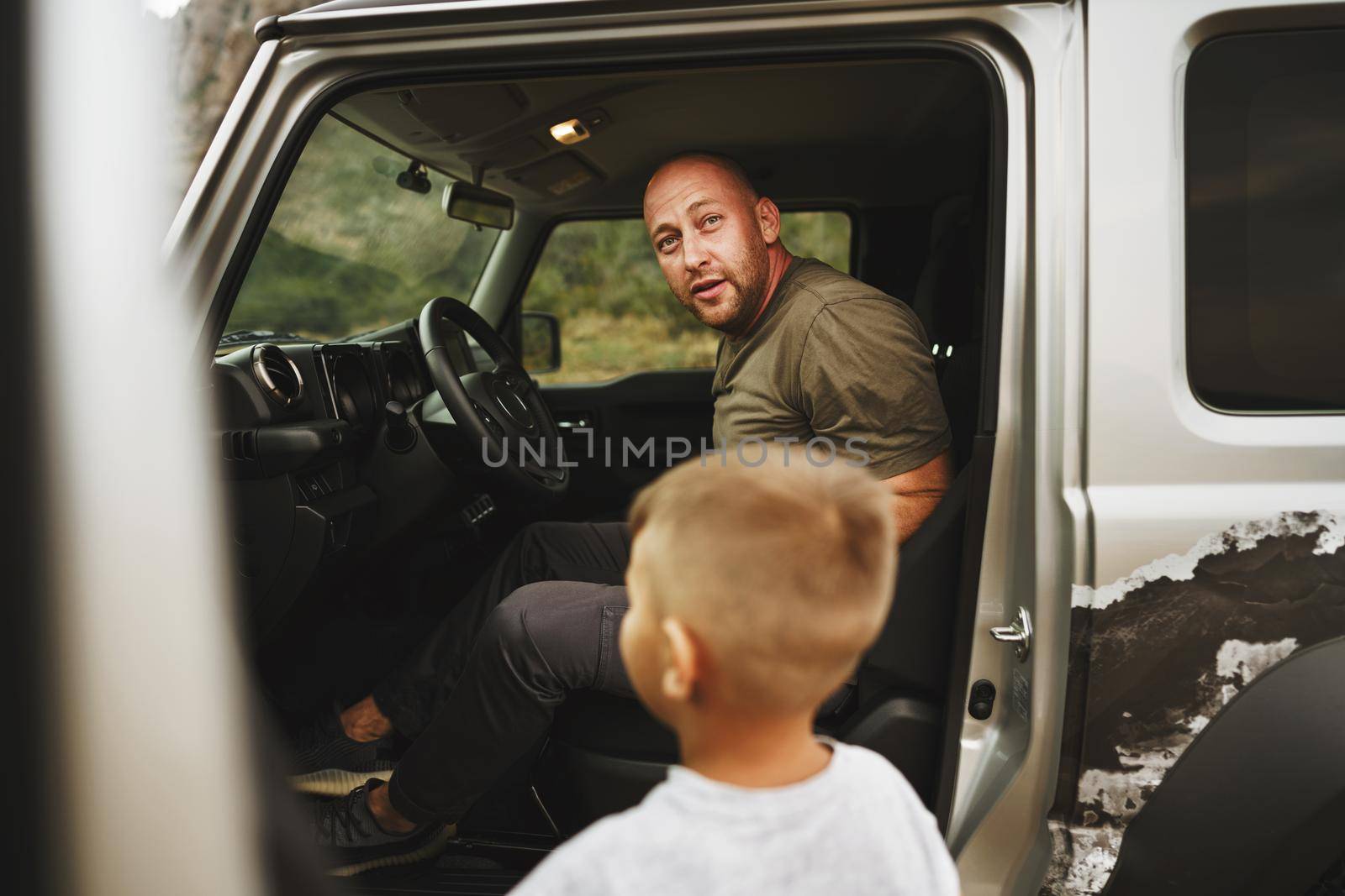 Father and little son standing near car on road trip, close up