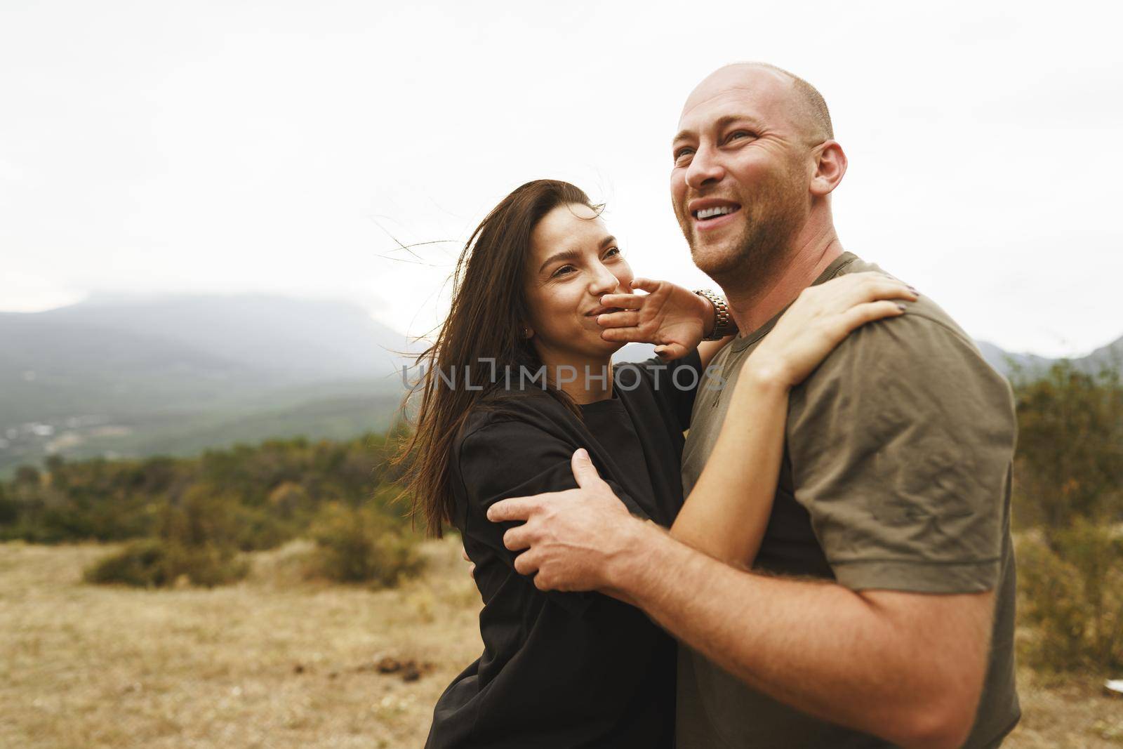 Happy couple in love hugging smiling and having fun in the mountains on foggy day