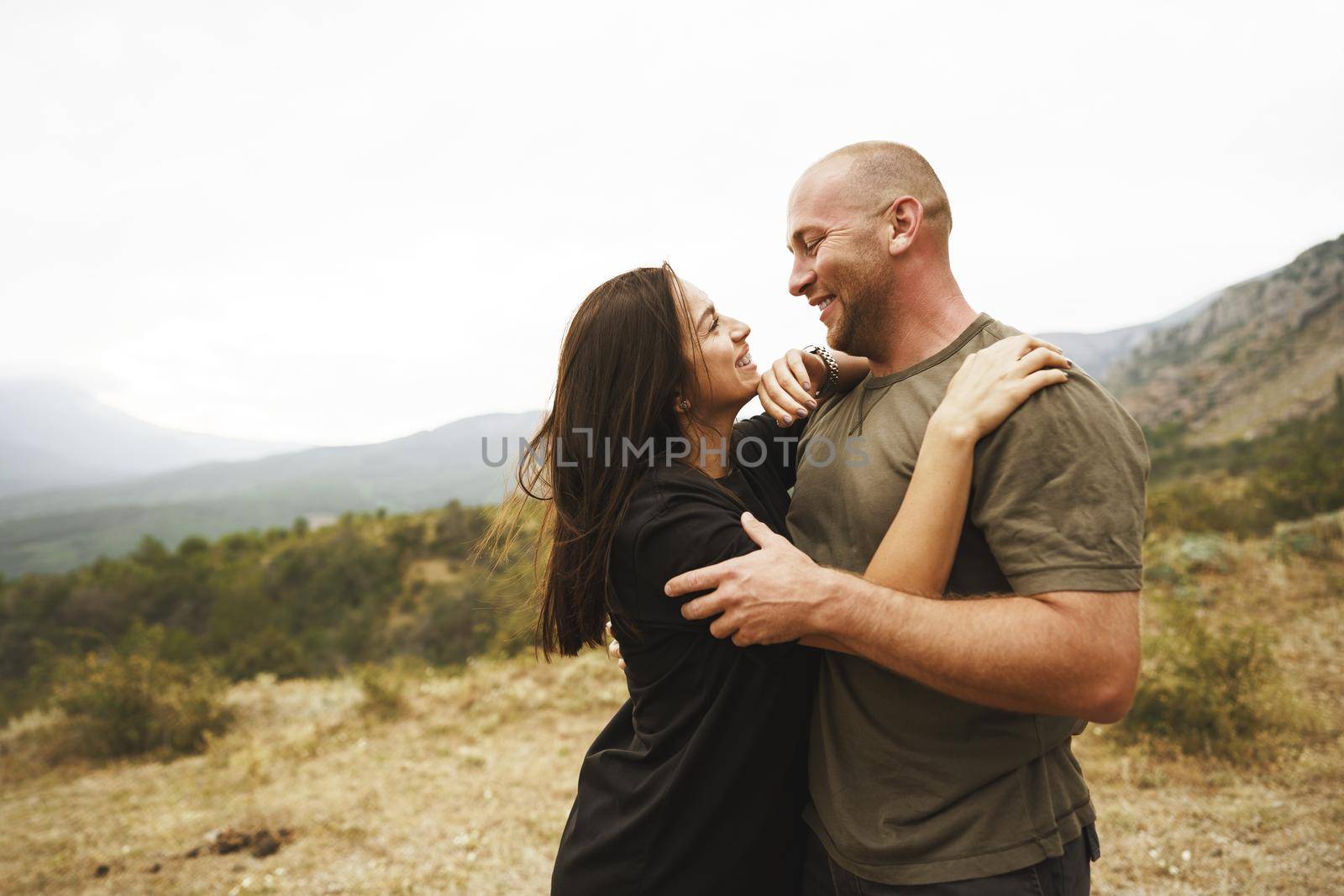 Happy couple in love hugging smiling and having fun in the mountains on foggy day