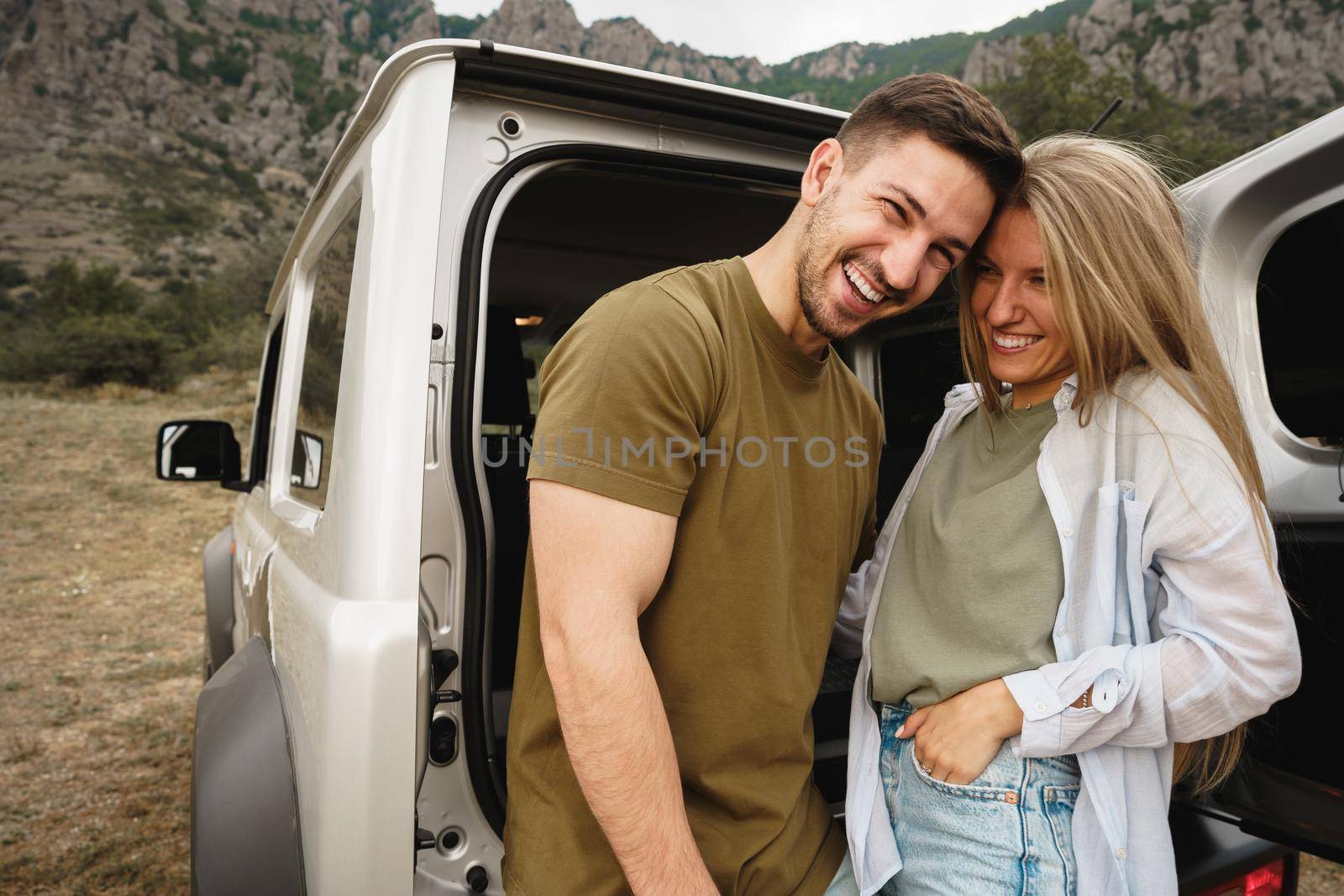 Young happy couple on a road trip sitting in car trunk outdoor