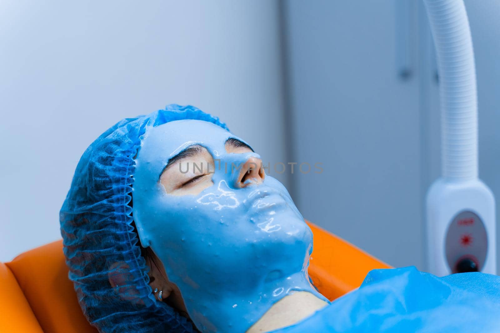 Alginate moisturizing mask for face and skin of young girl. Spa procedure for rejuvenation. beautician smears blue mask. Dermatology in medical clinic