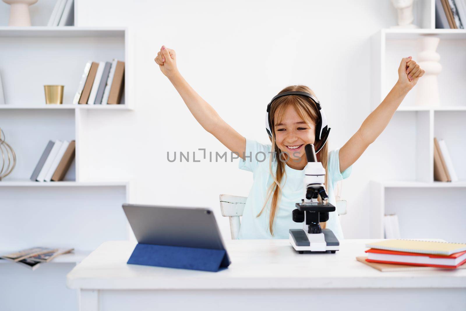 Young girl using microscope during online lesson education at home, close up
