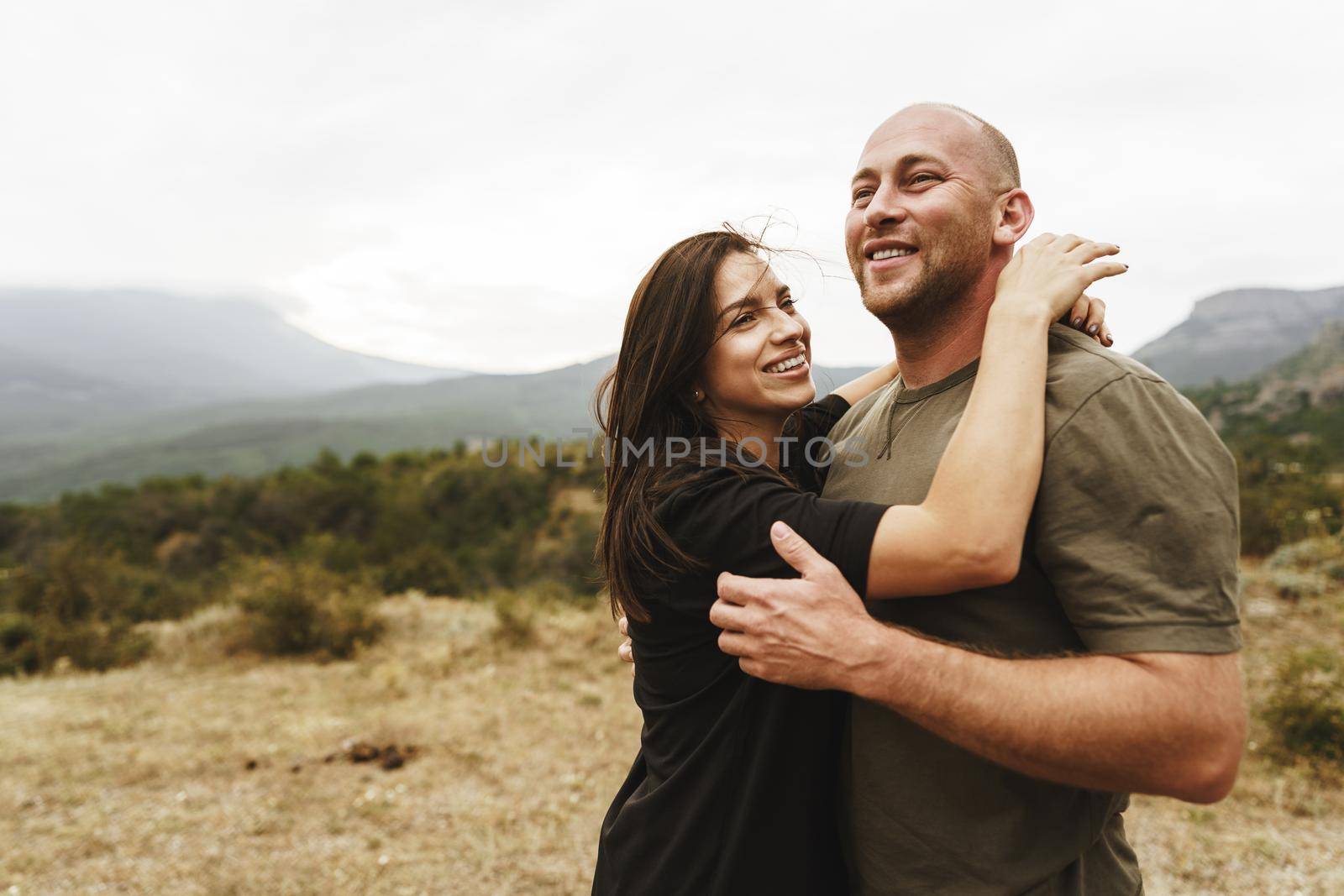 Happy couple in love hugging smiling and having fun in the mountains on foggy day