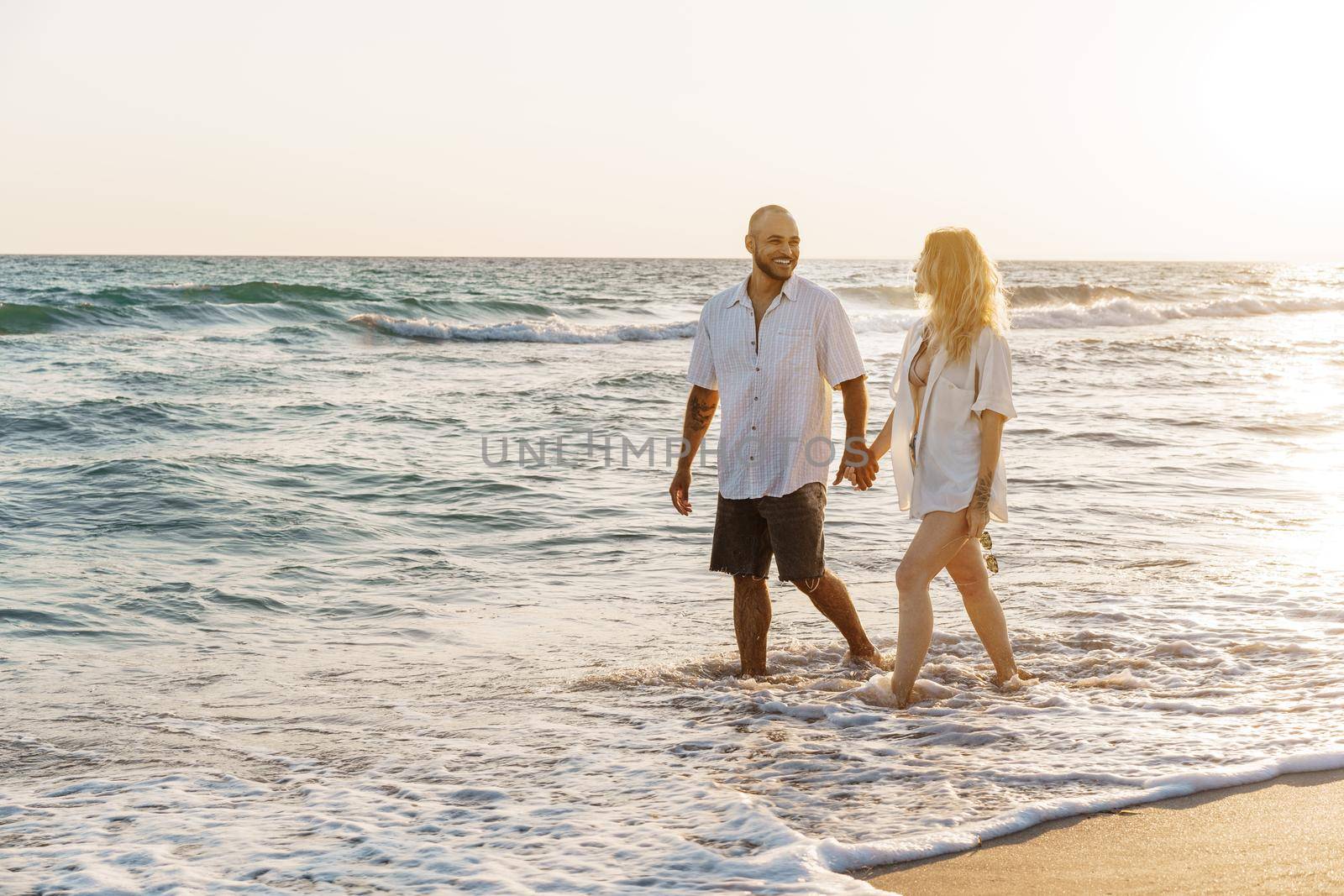 Young beautiful couple walking on beach near sea by Fabrikasimf