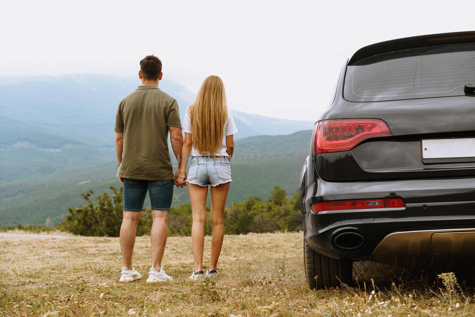Young couple on road trip relaxing and enjoying the view of mountains