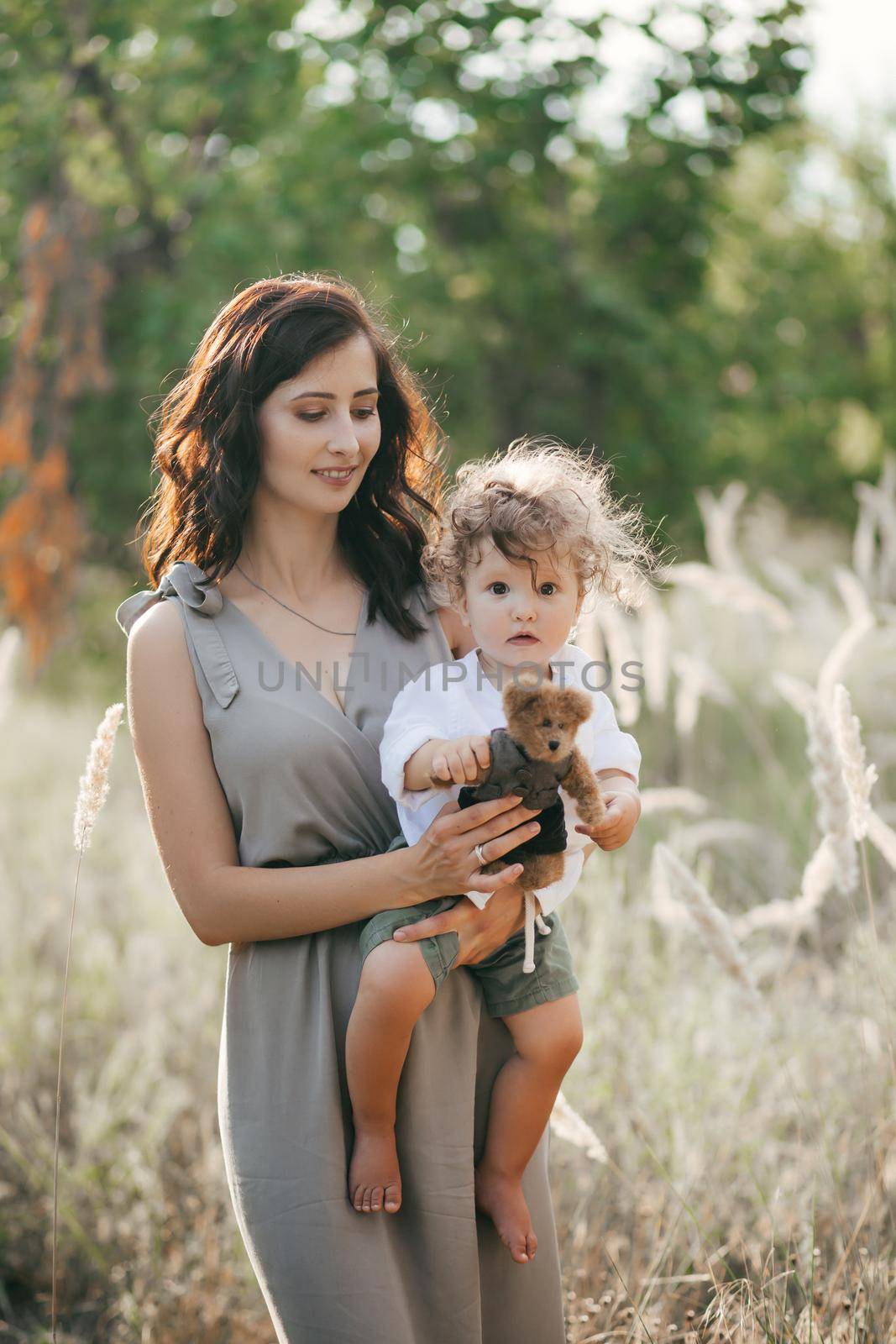 Happy young woman with children on wheat summer field. Happy motherhood. Adventure, travel, tourism, hike and people concept - happy family walking