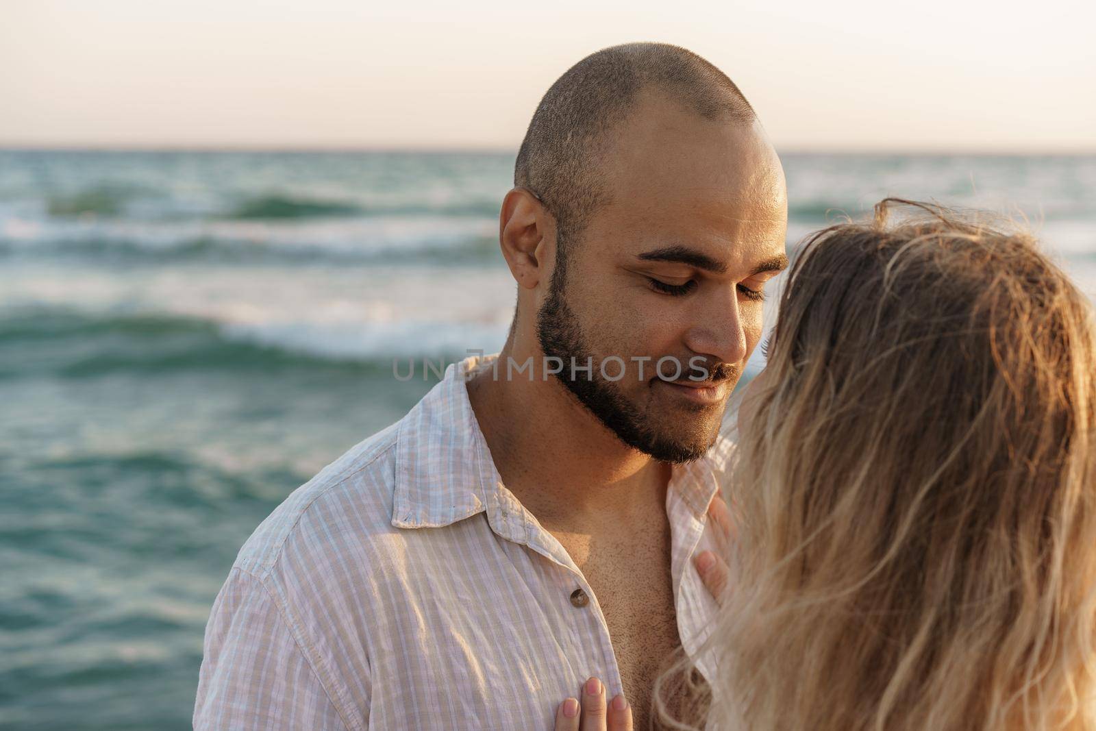 Portrait of happy young couple in love embracing each other on beach, close up