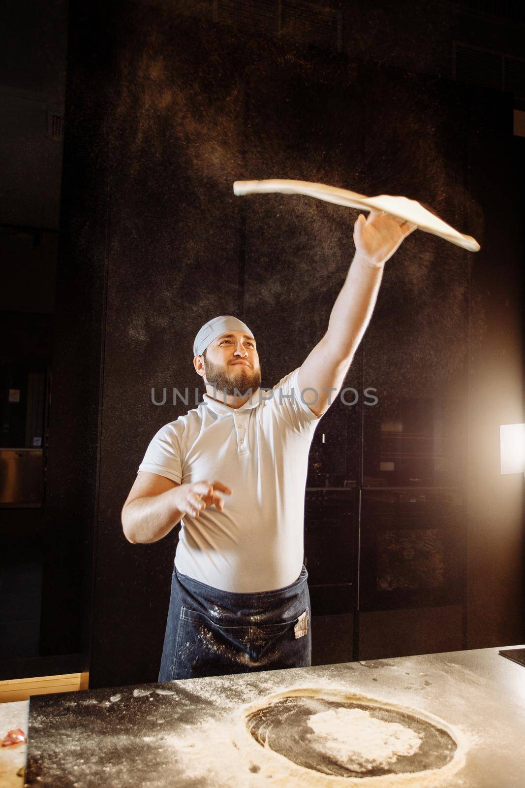 Skilled chef throwing up pizza base dough by Gravika