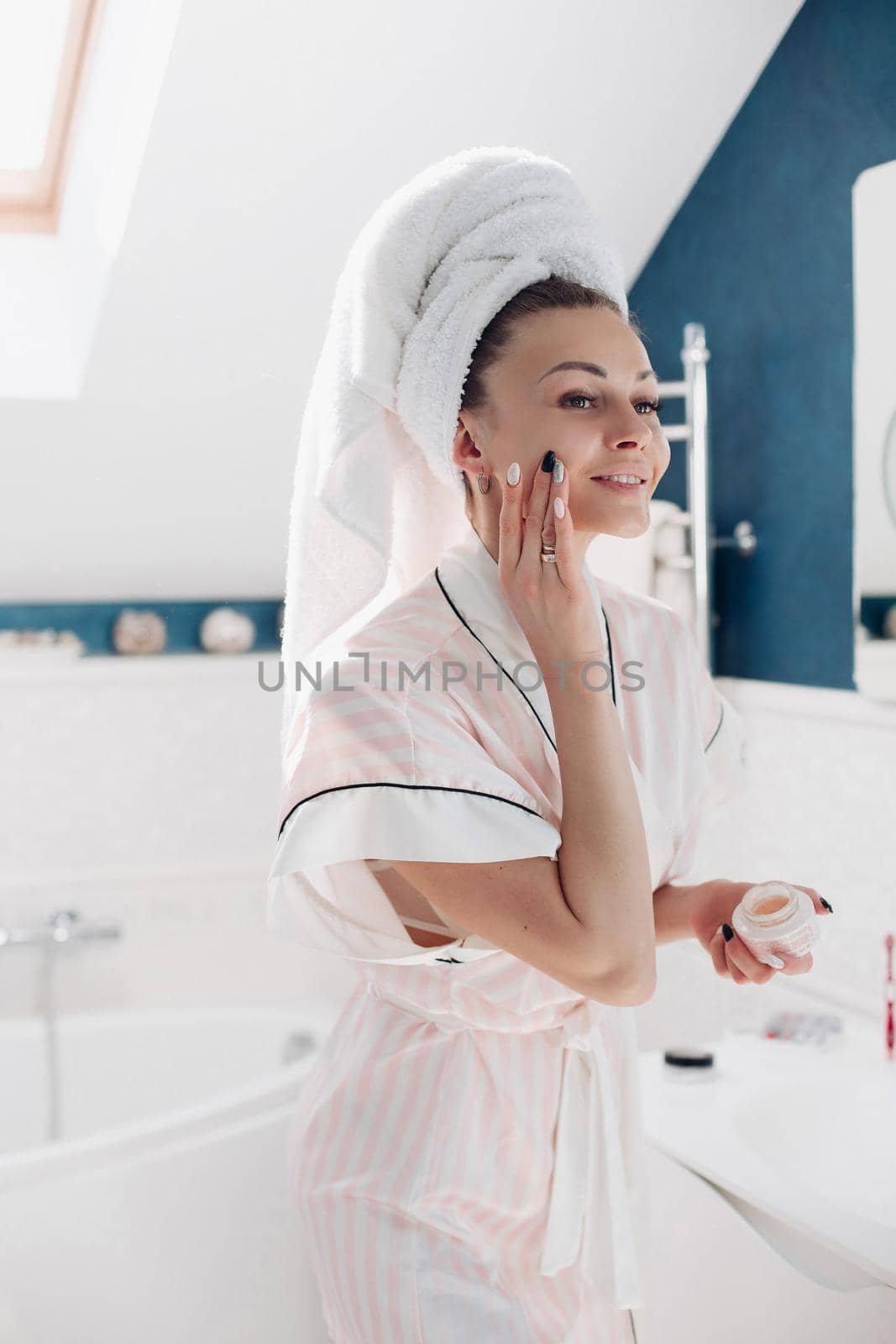 Young lady standing in light bathroom after morning shower. by StudioLucky