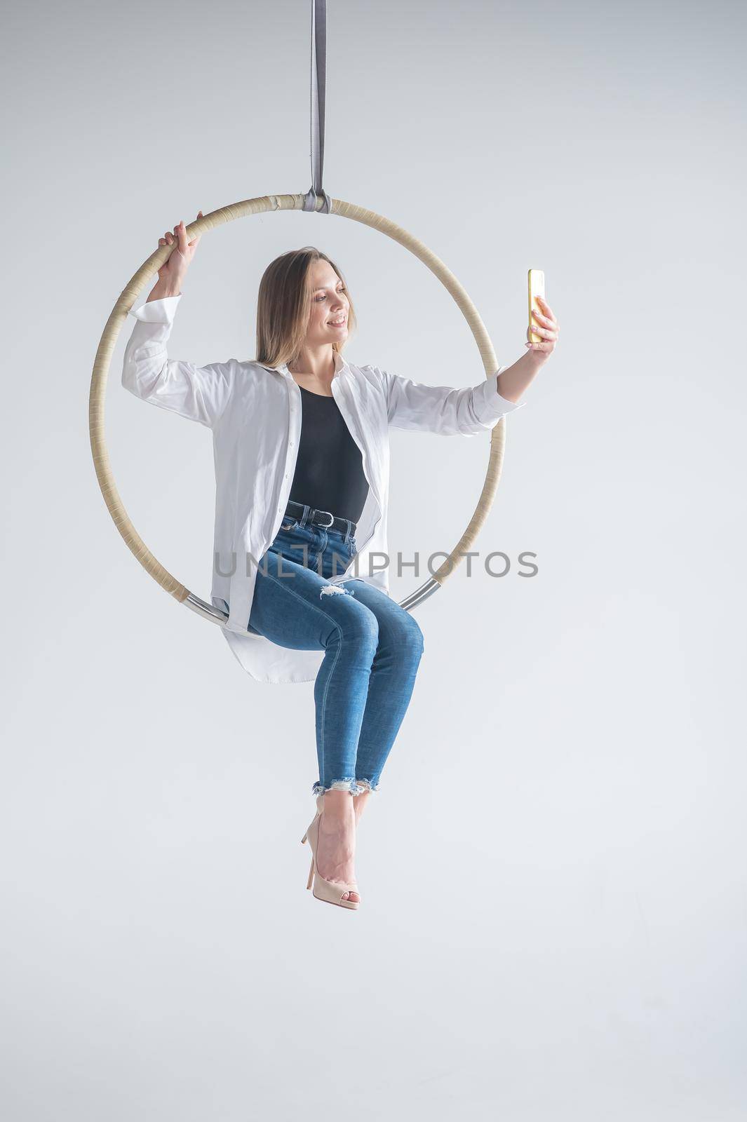 Caucasian woman gymnast on an aerial hoop takes a selfie on a smartphone. by mrwed54
