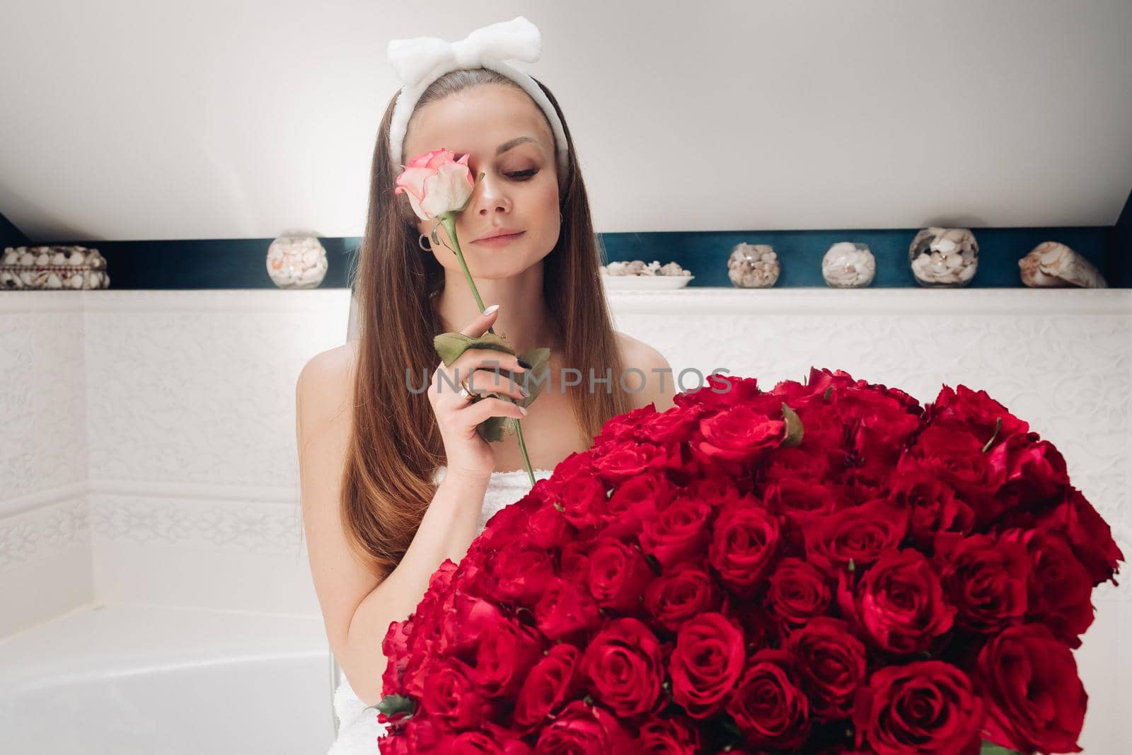 Attractive woman in towel and headband with bouquet of red roses. by StudioLucky