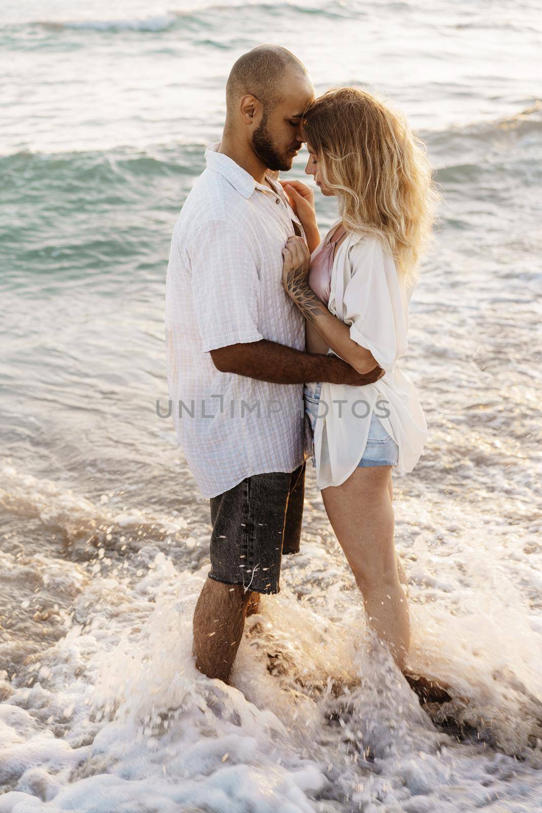 Beautiful young couple hugging on the beach by the water, close up
