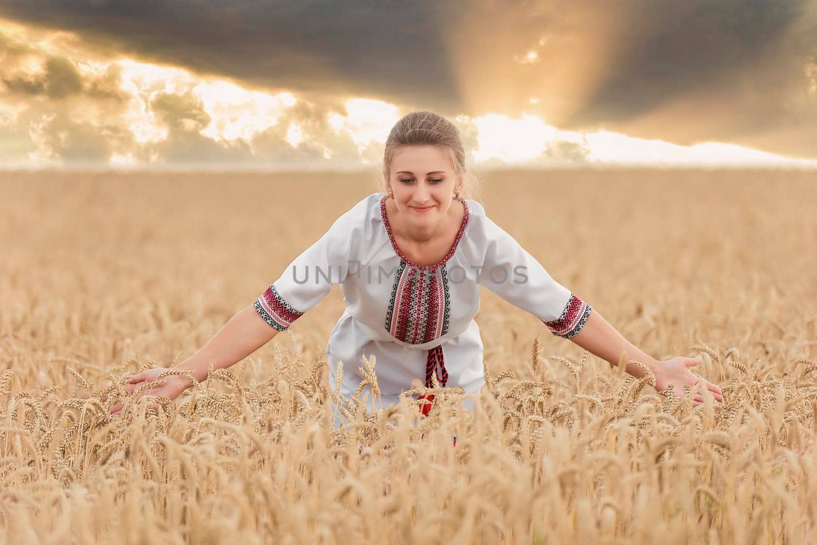 girl in an embroidered shirt on a wheat field and a sunset sky