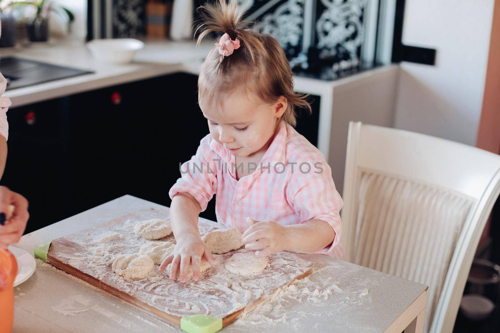 Cute child in flour cooking together with parent at kitchen. by StudioLucky