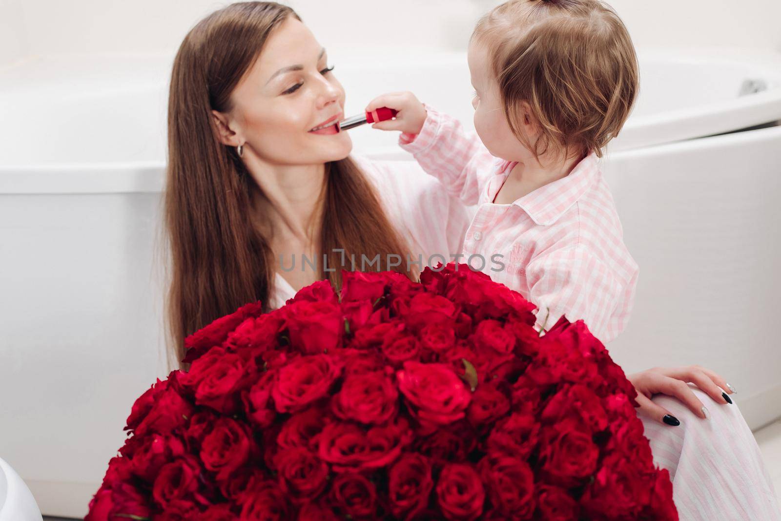 Beautiful mother posing with girl and big bouquet of roses by StudioLucky