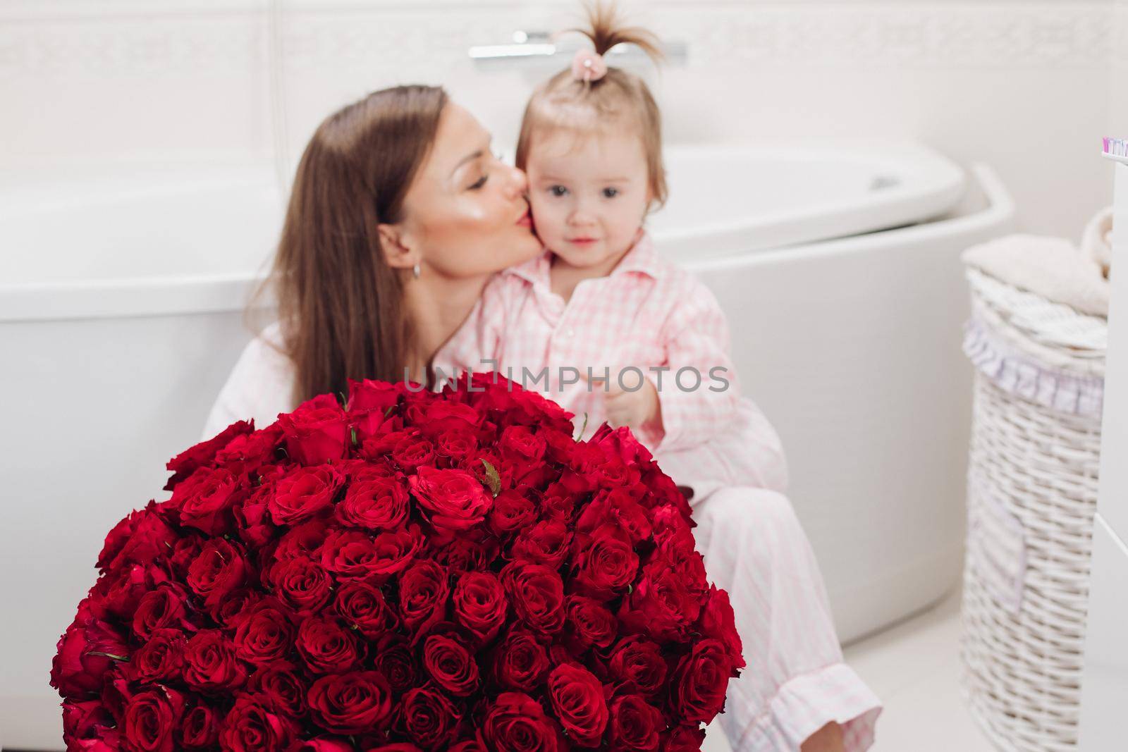 Beautiful mother posing with girl and big bouquet of roses by StudioLucky