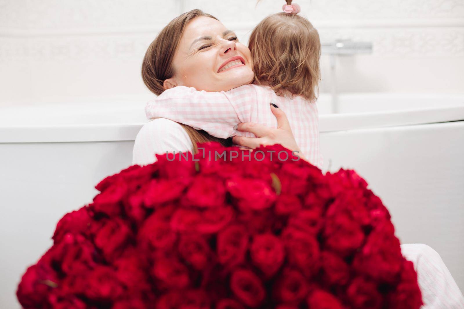 Beautiful mother posing with girl and big bouquet of roses by StudioLucky