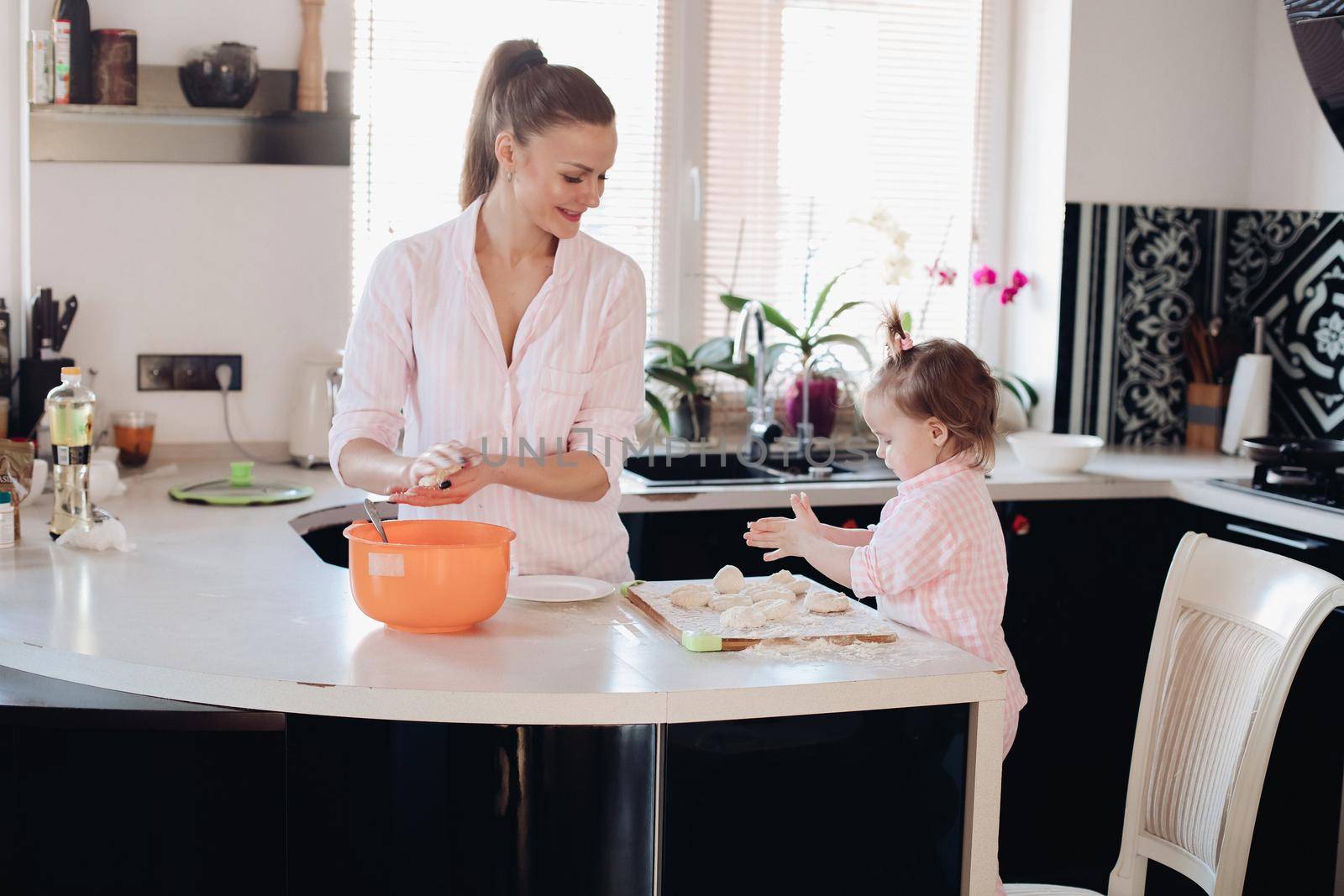 Little lovely kid helping parent with dough at kitchen. by StudioLucky