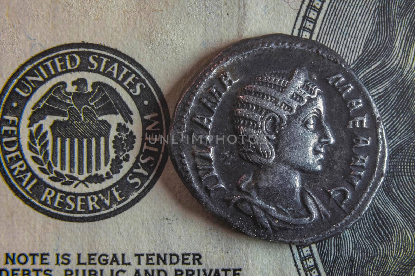 An old Roman coin lies on a 100 dollar bill by zokov