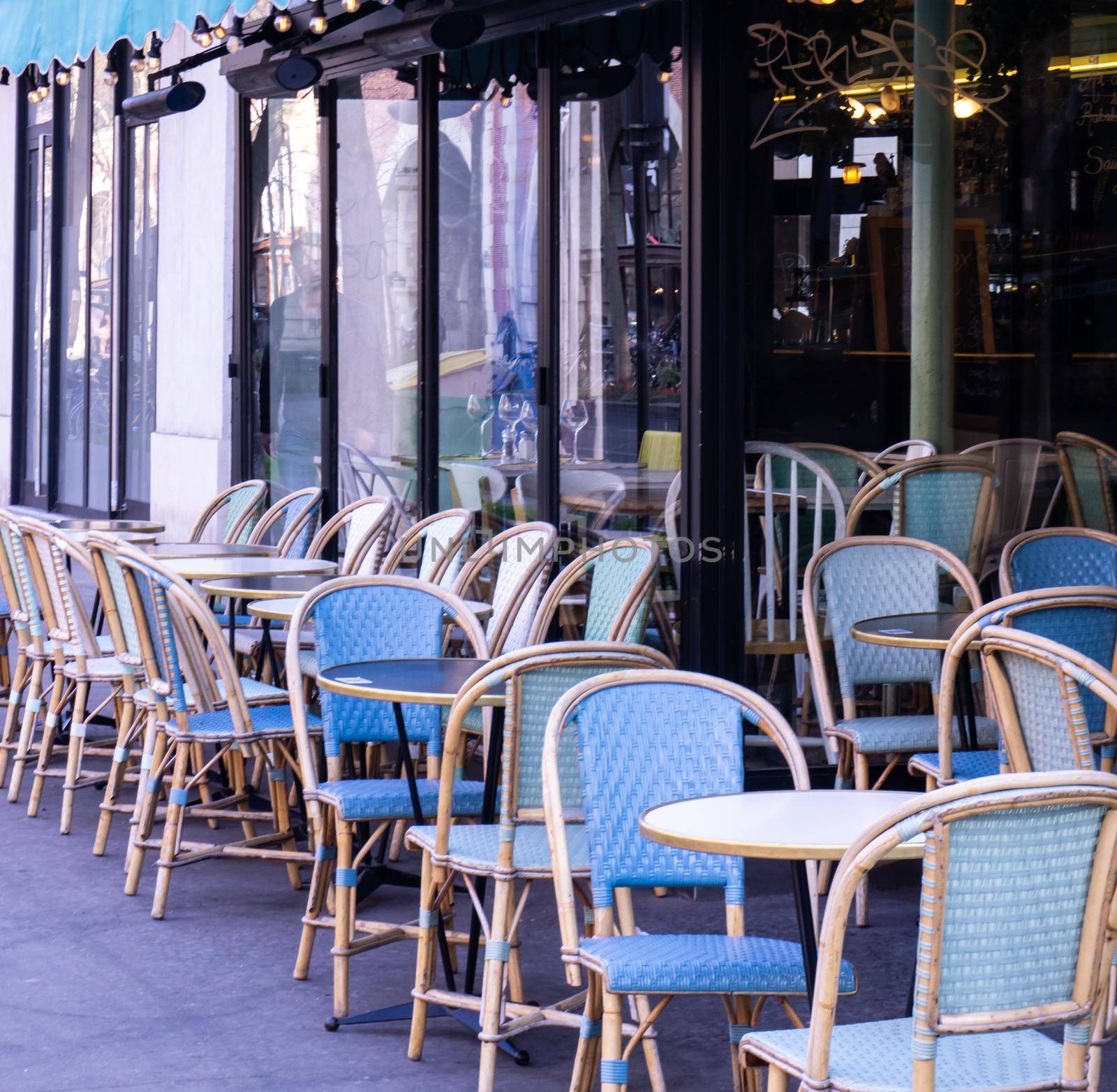 Empty Parisian street cafe with wicker chairs during the day