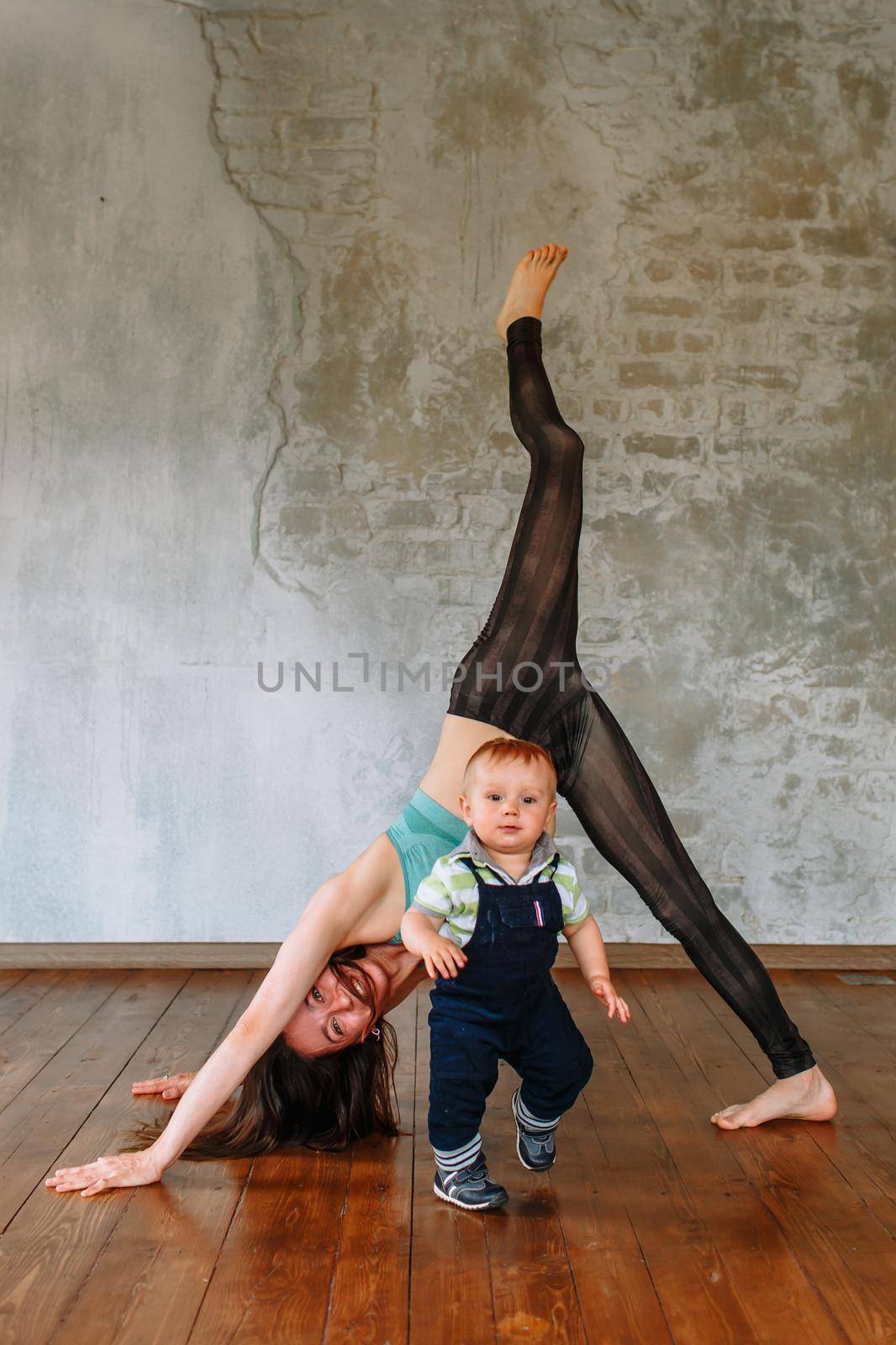 Yoga girl performs an exercise, next to her little son