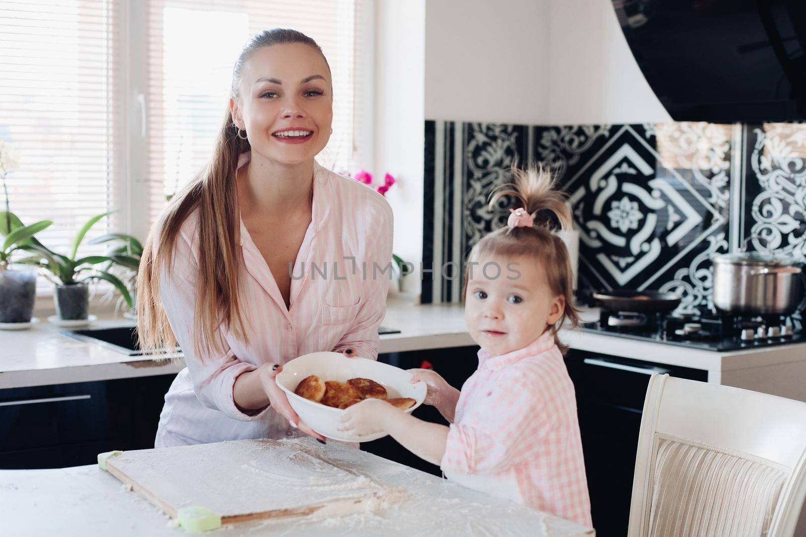 Beautiful woman with lovely child holding bowl with cookies. by StudioLucky