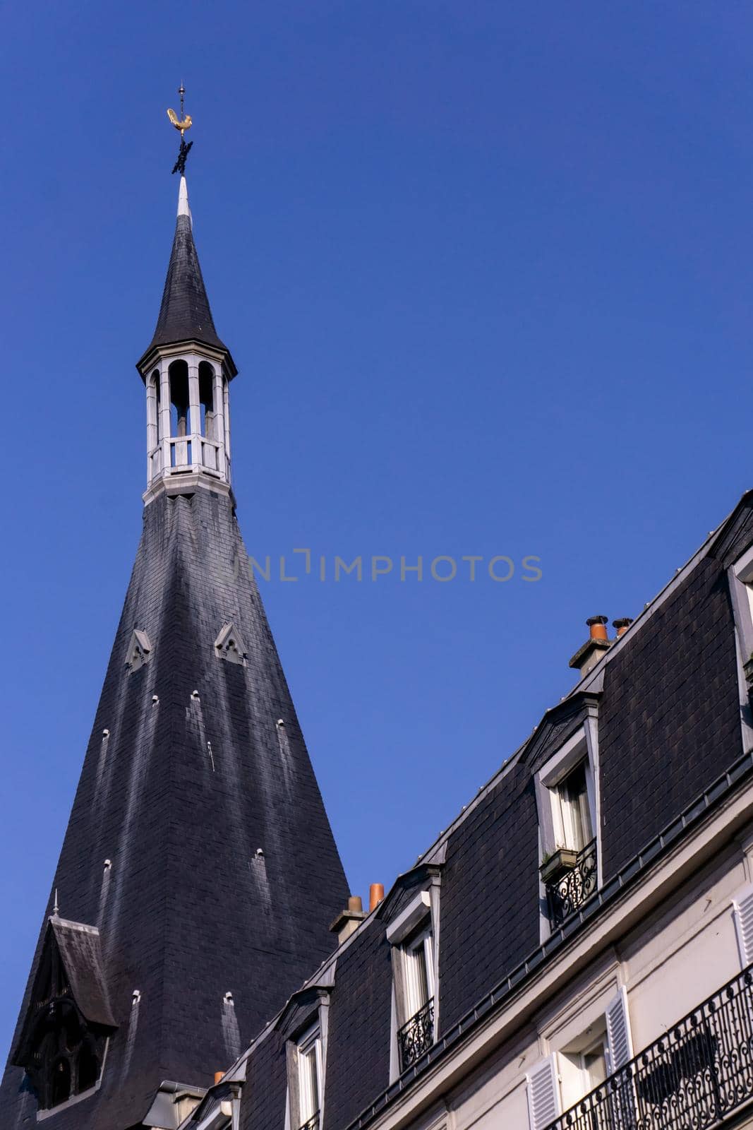 Parisian tiled roofs with spire and chimneys on a sunny day