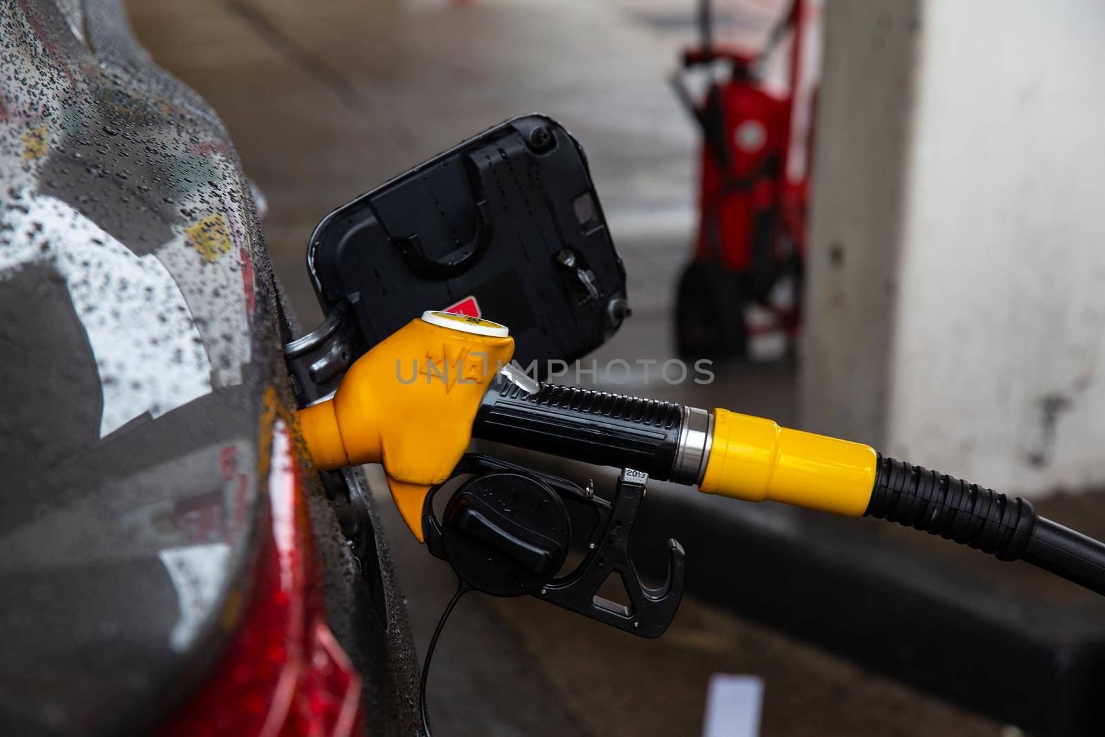 The fuel pistol is installed in the vehicle tank, yellow fuel gun. Car refueling and fuel prices concept.